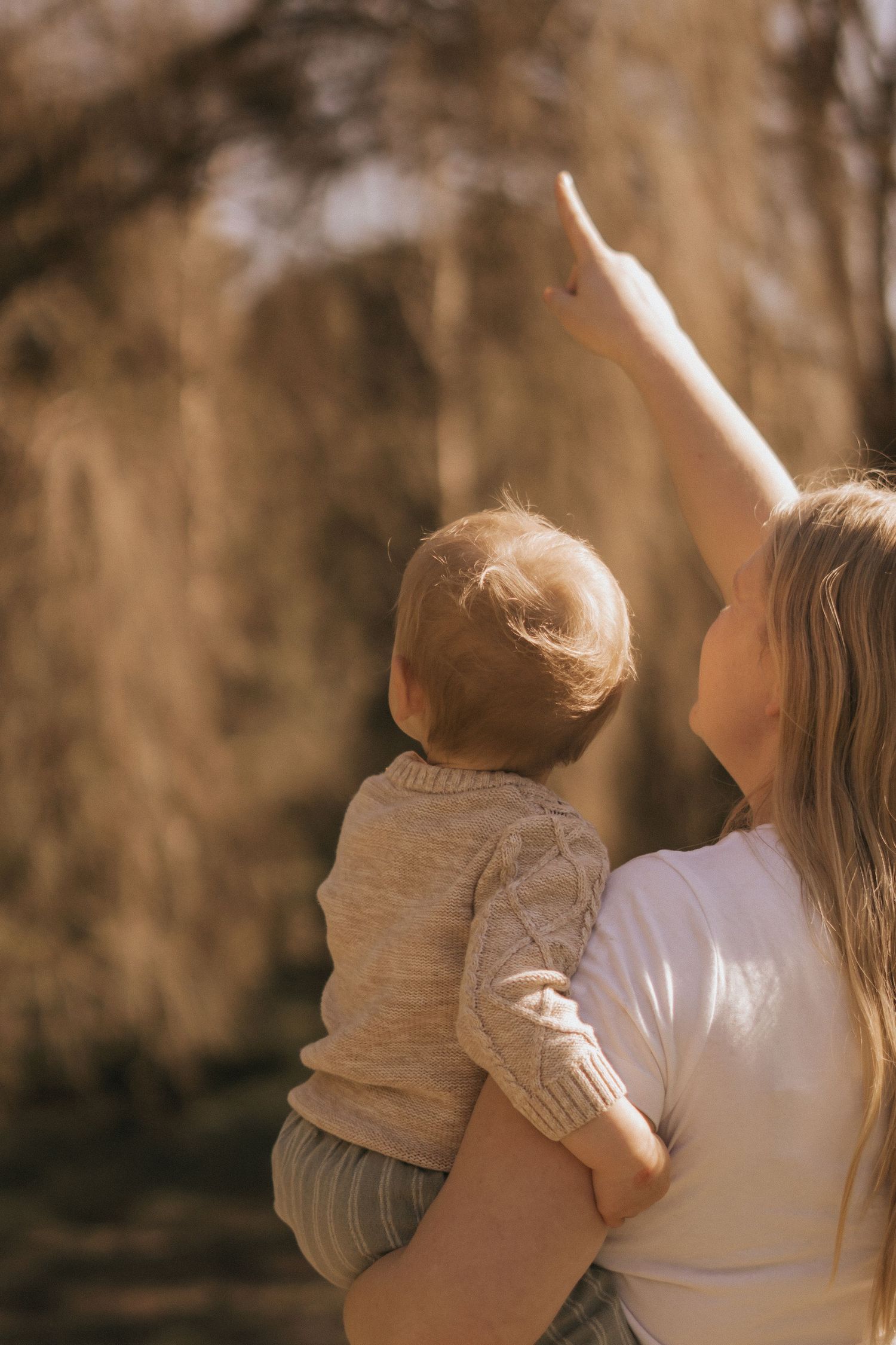 Silhouette of parent and child playing together at sunset in a park.