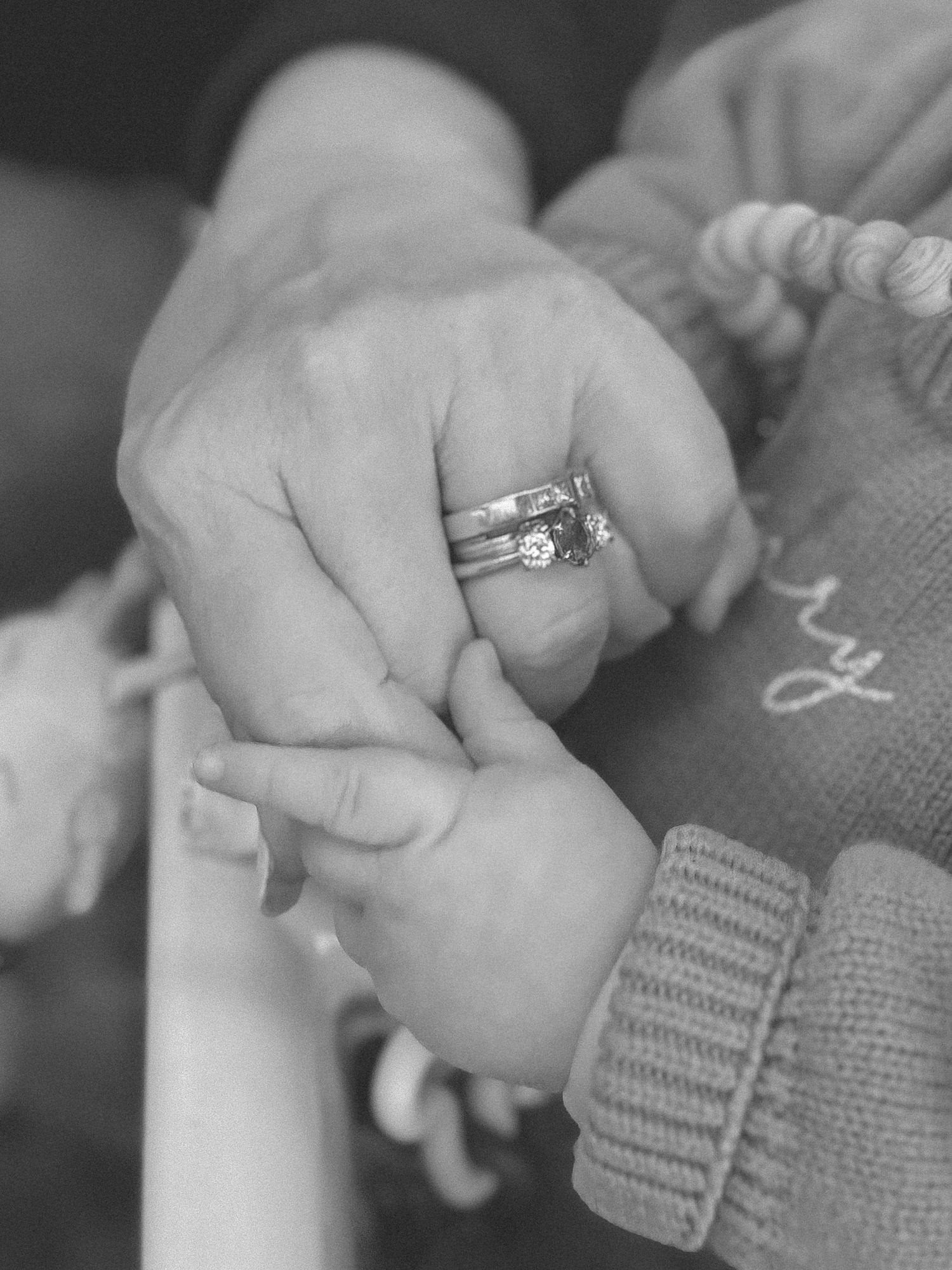 Close-up of hands holding with engagement ring visible.