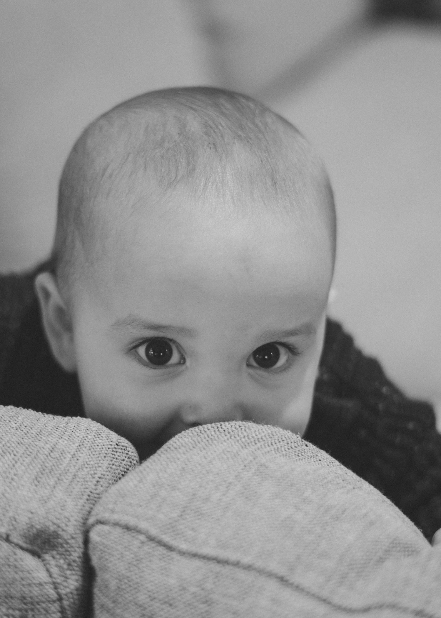 Close-up black and white photo sequence of baby's eyes peeking over blanket.