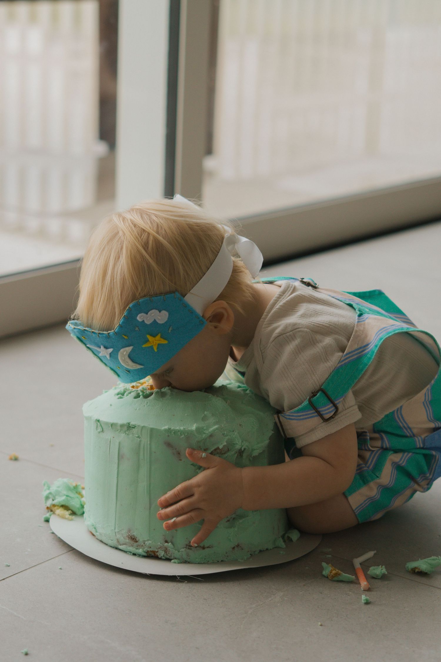 A sequence of photos showing someone face-planting into a mint green birthday cake on a white plate near a window.