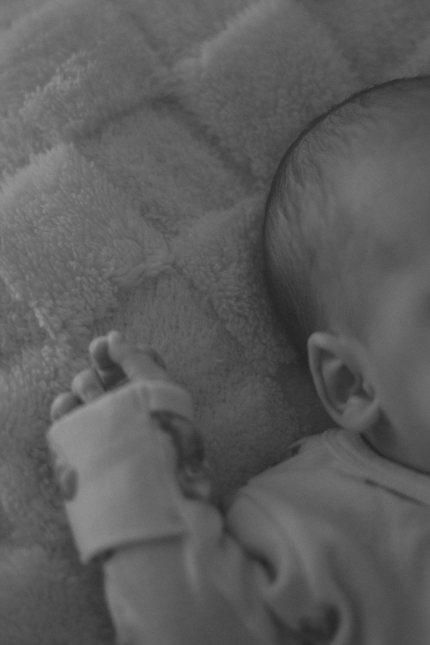 Close-up black and white shot of a sleeping baby's face against a soft blanket.