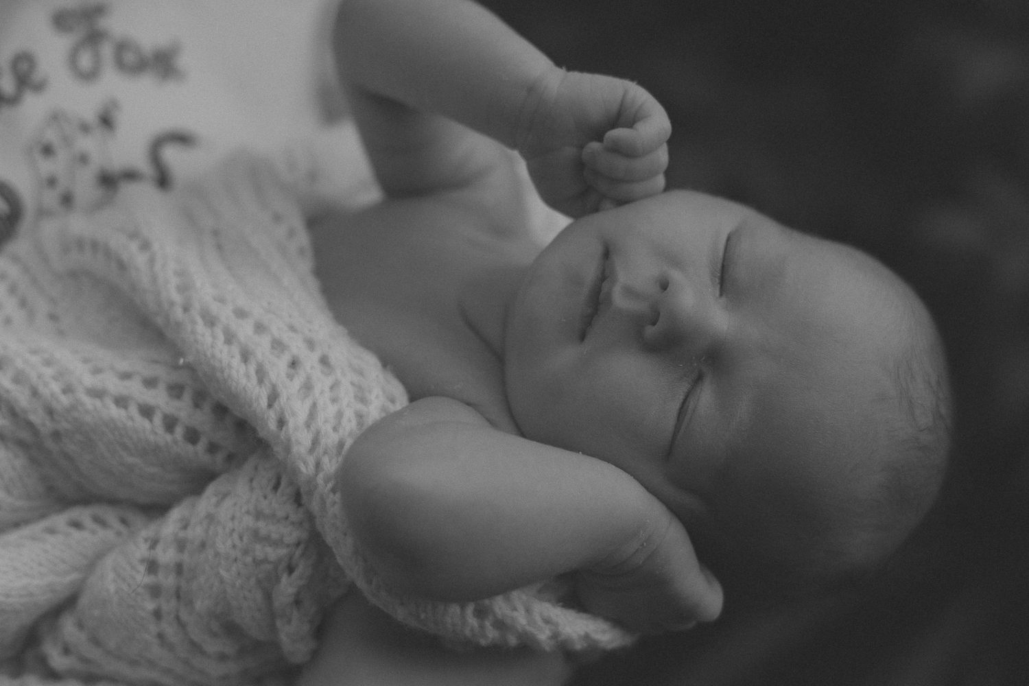 Black and white portrait of a sleeping infant wrapped in a cozy knit sweater.