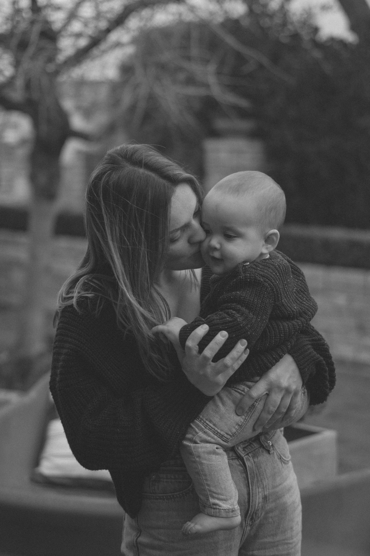 A series of tender black and white photos showing affectionate moments between parent and child outdoors.