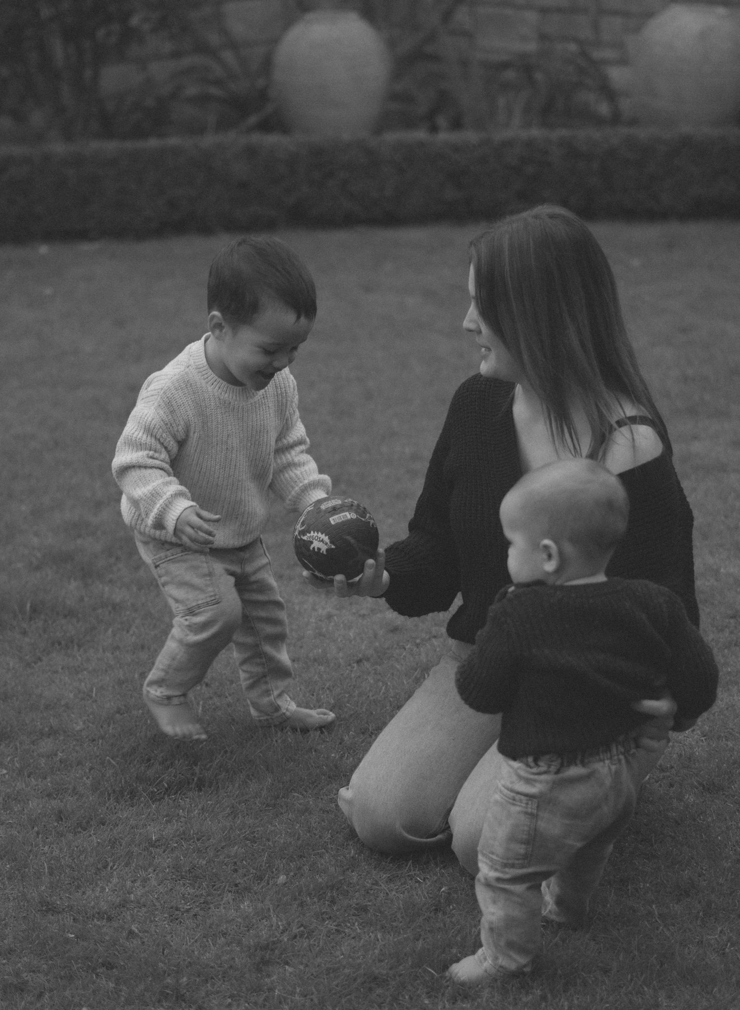 Black and white photos showing playful interactions between adults and children on grass.