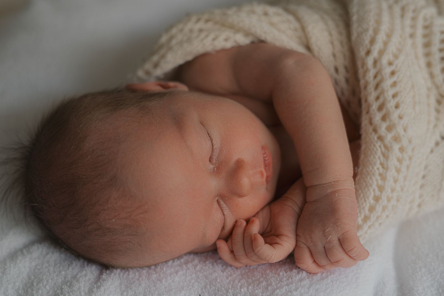 Artistic black and white photo series showing a sleeping newborn baby against soft white textiles.
