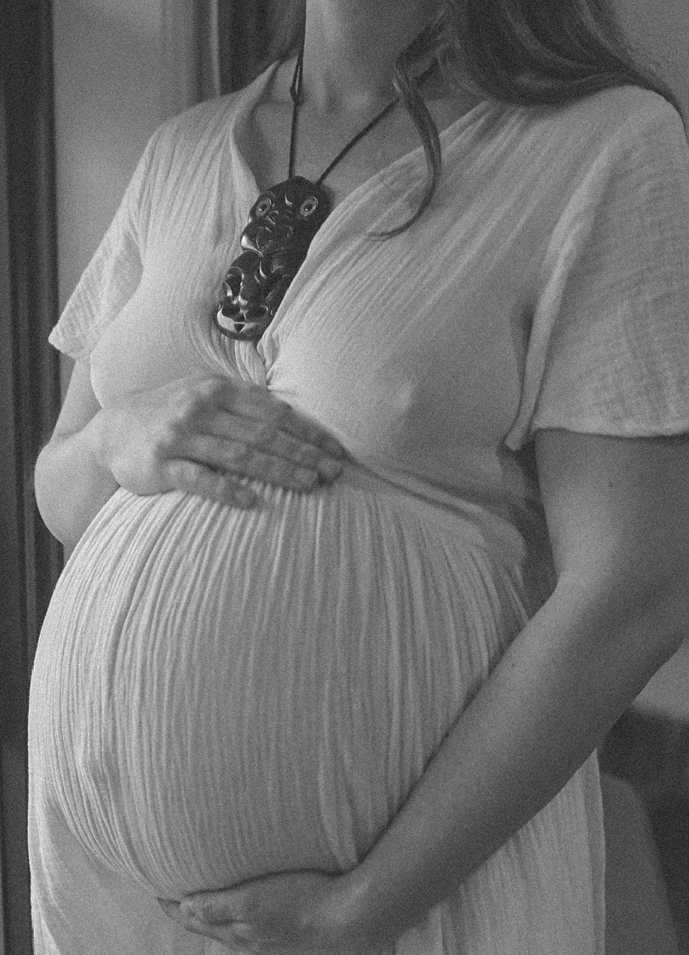 A series of photos showing a pregnant belly in a white dress against a window.