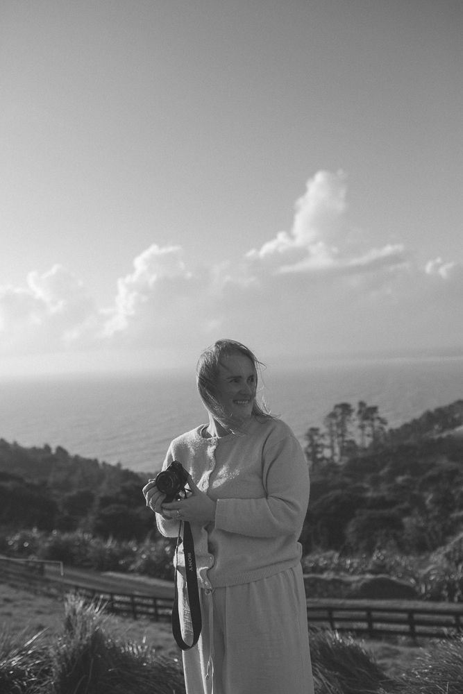 Person with camera photographing scenic mountain landscape in black and white.