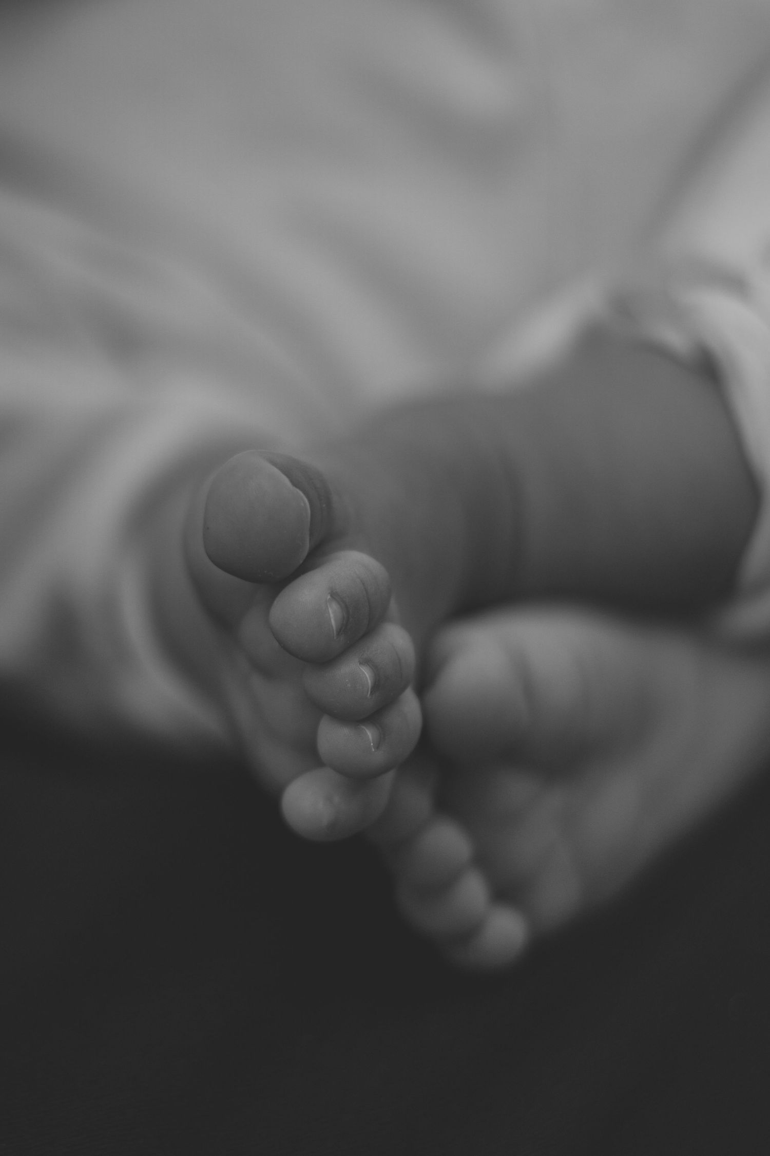 A series of black and white macro photos showing a baby's tiny feet in soft focus.