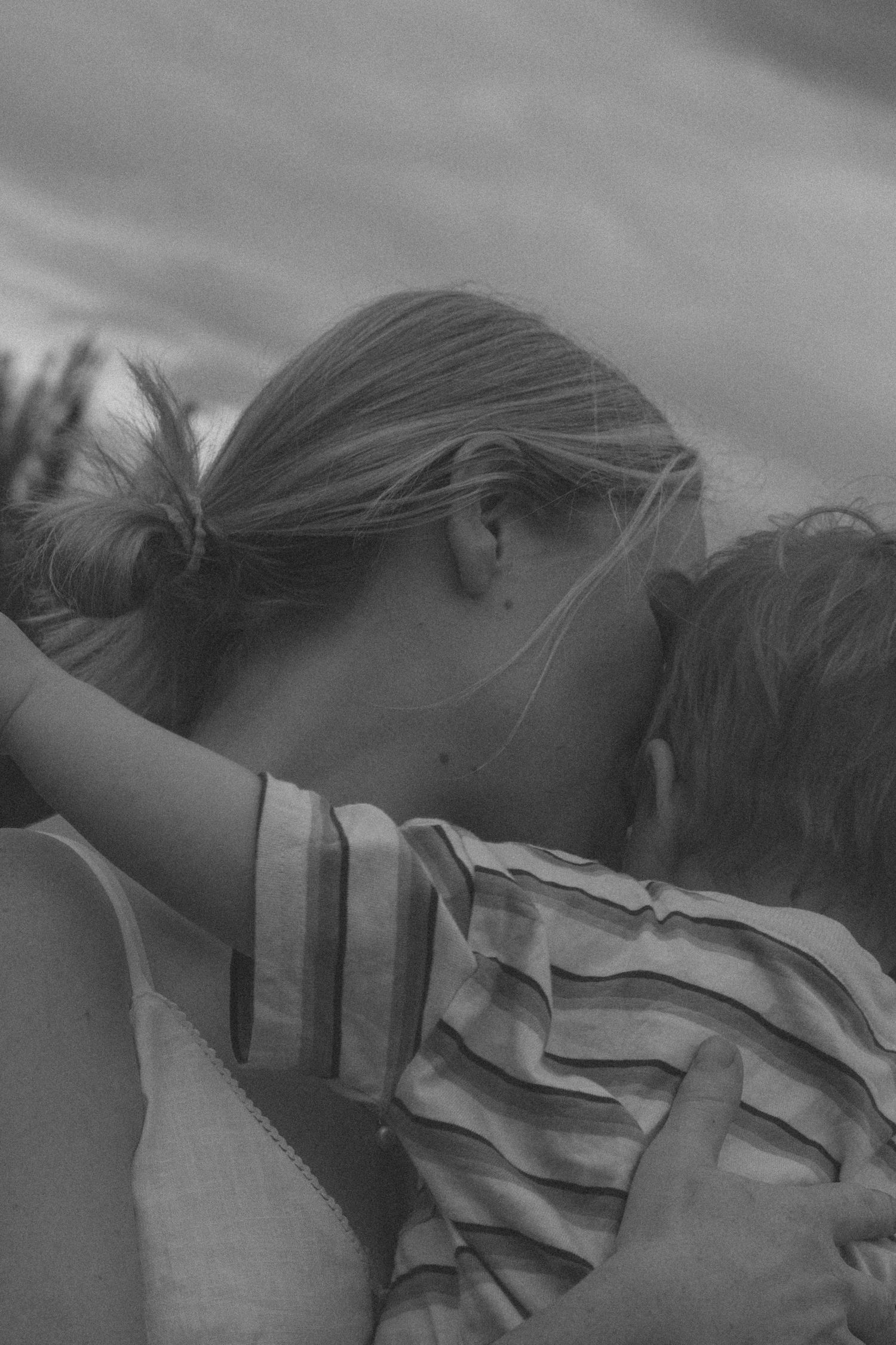 A tender black and white moment captured showing an intimate embrace between two people in striped clothing.