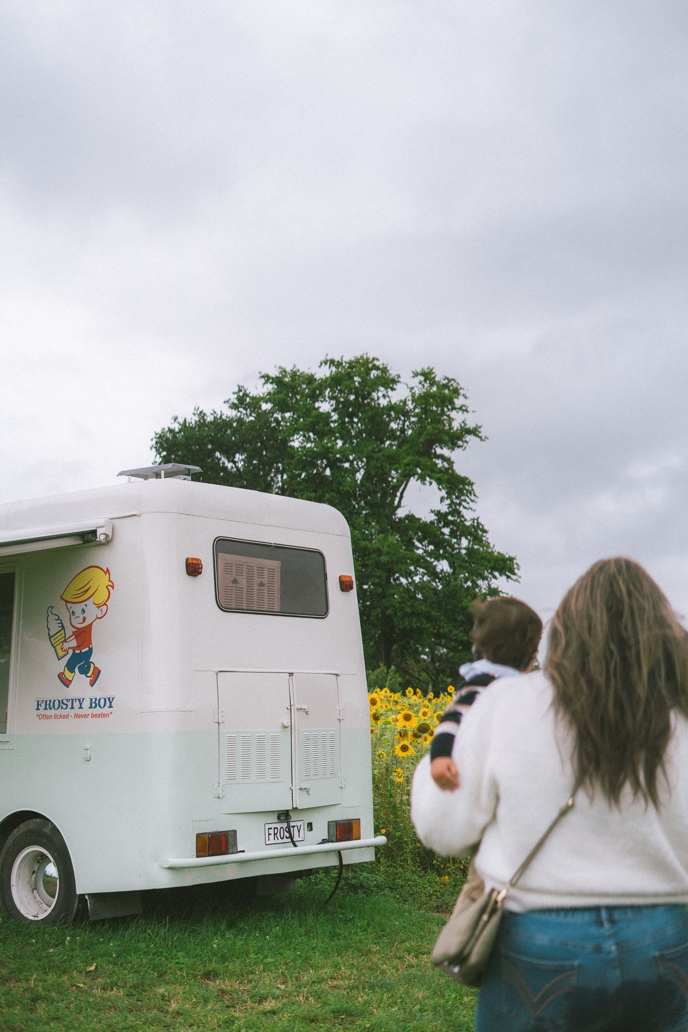 A series of four photos showing a white camper trailer parked in a field with yellow flowers and trees in the background.