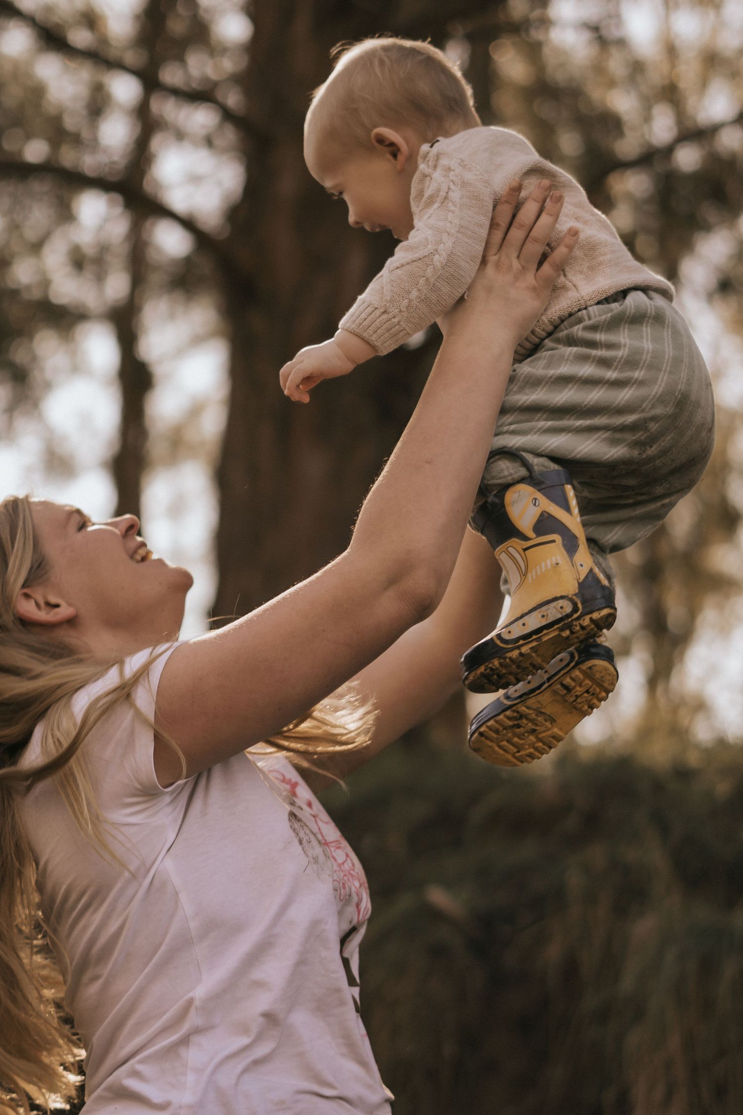 Parent playfully lifting child in the air during golden hour outdoors.