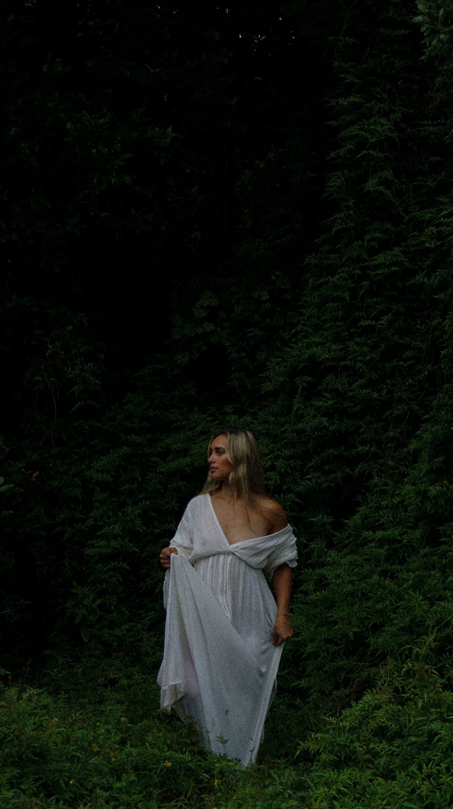 Figure in white clothing moving through shadowy forest setting.