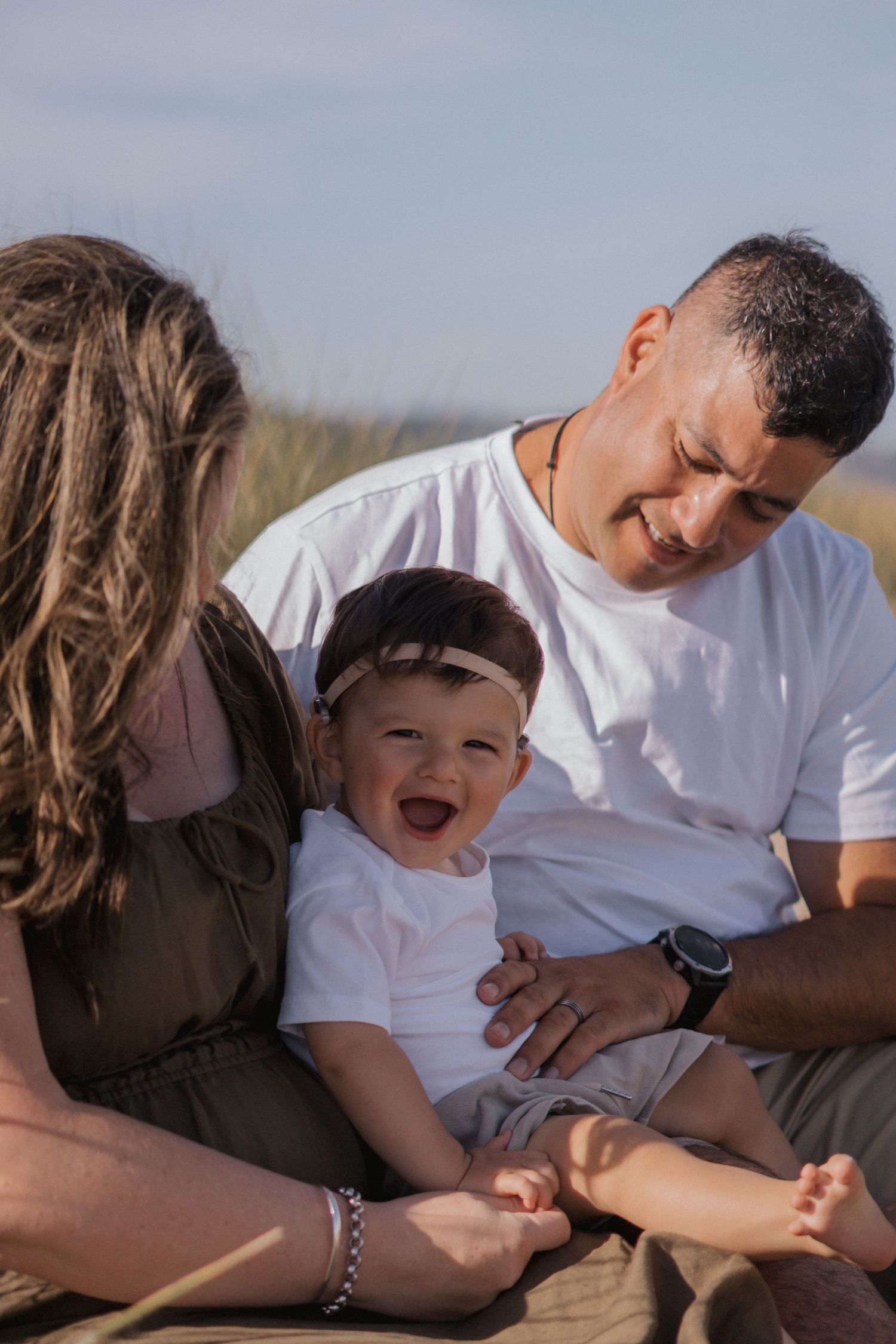A joyful family moment outdoors as they sit together on a blanket during golden hour.