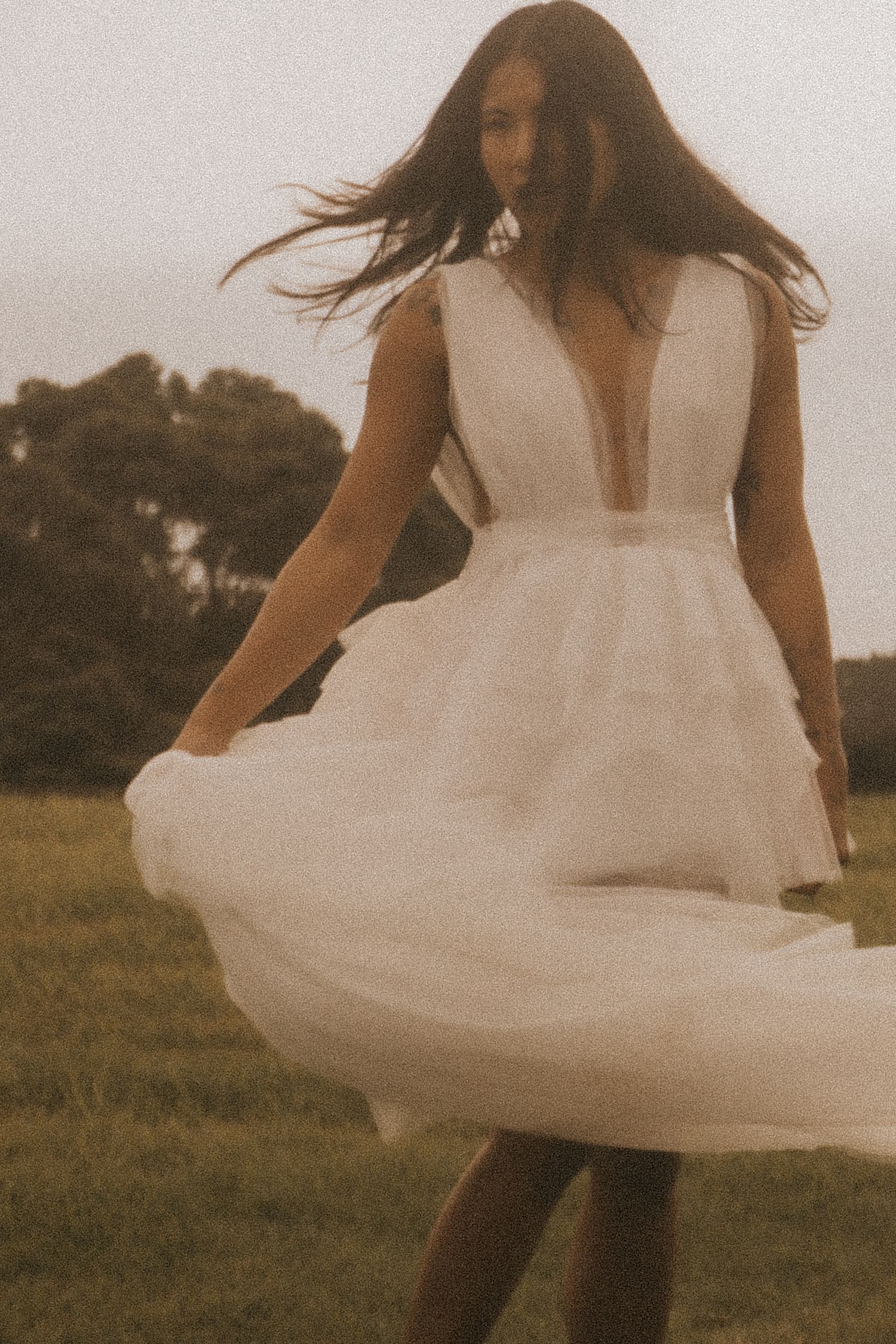 Person in white dress spinning gracefully in a sepia-toned field.
