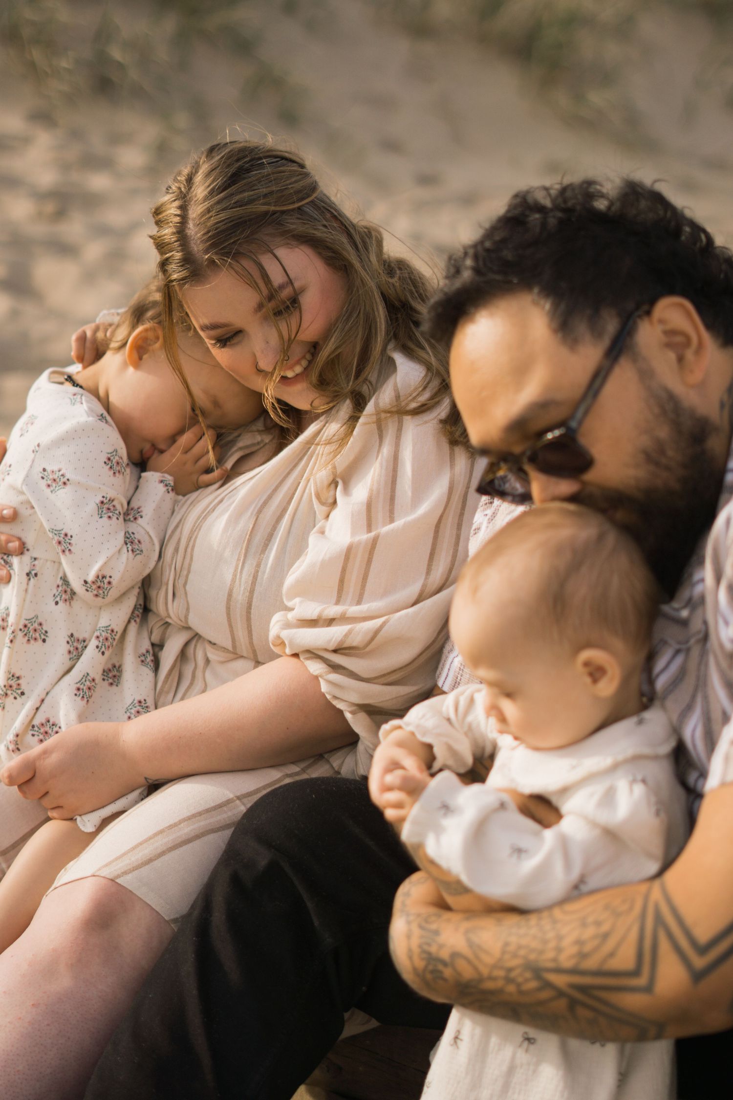 Intimate family moment captured in warm sunlight on a cozy blanket.