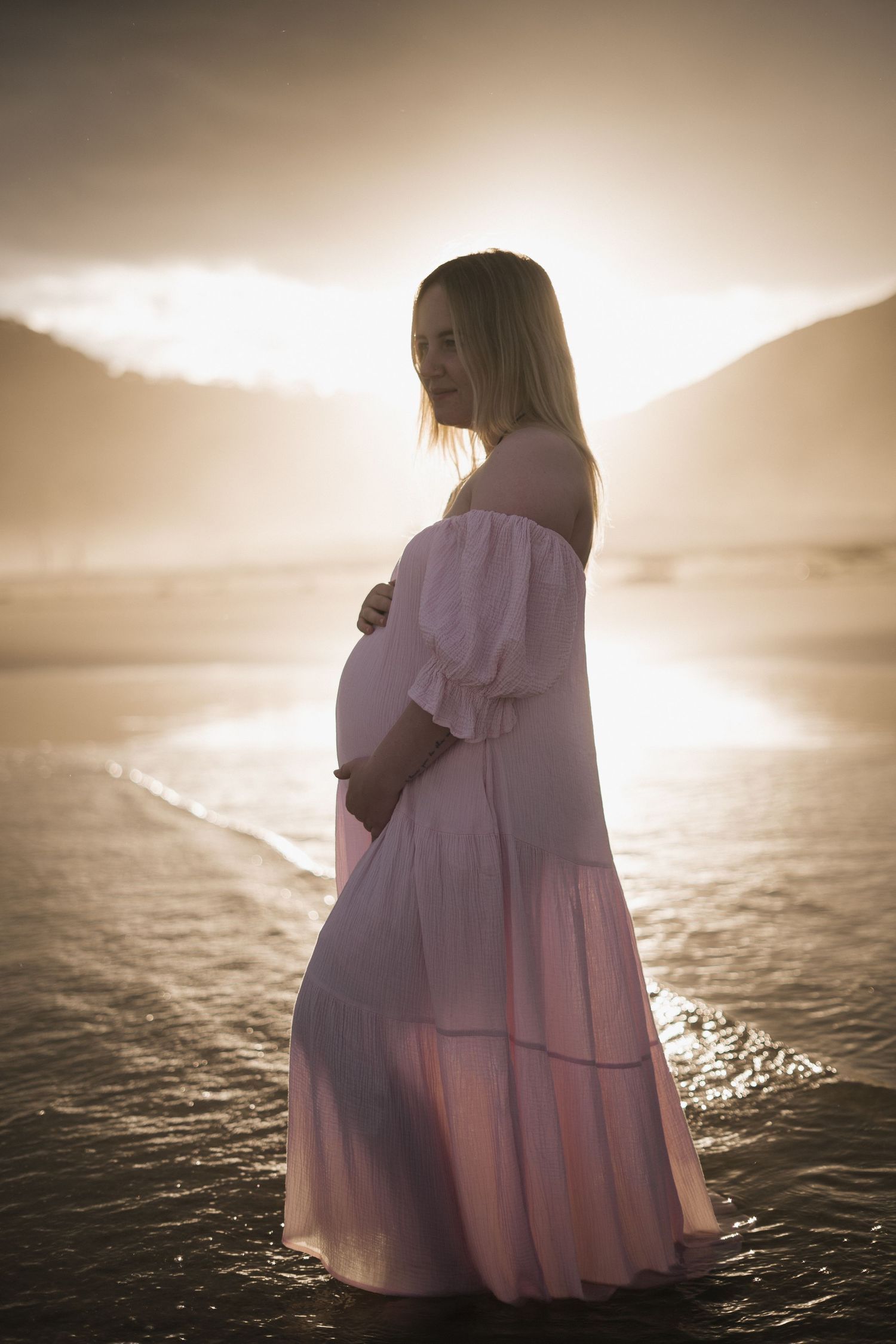 Silhouette of a person in flowing dress against a dramatic ocean sunset.