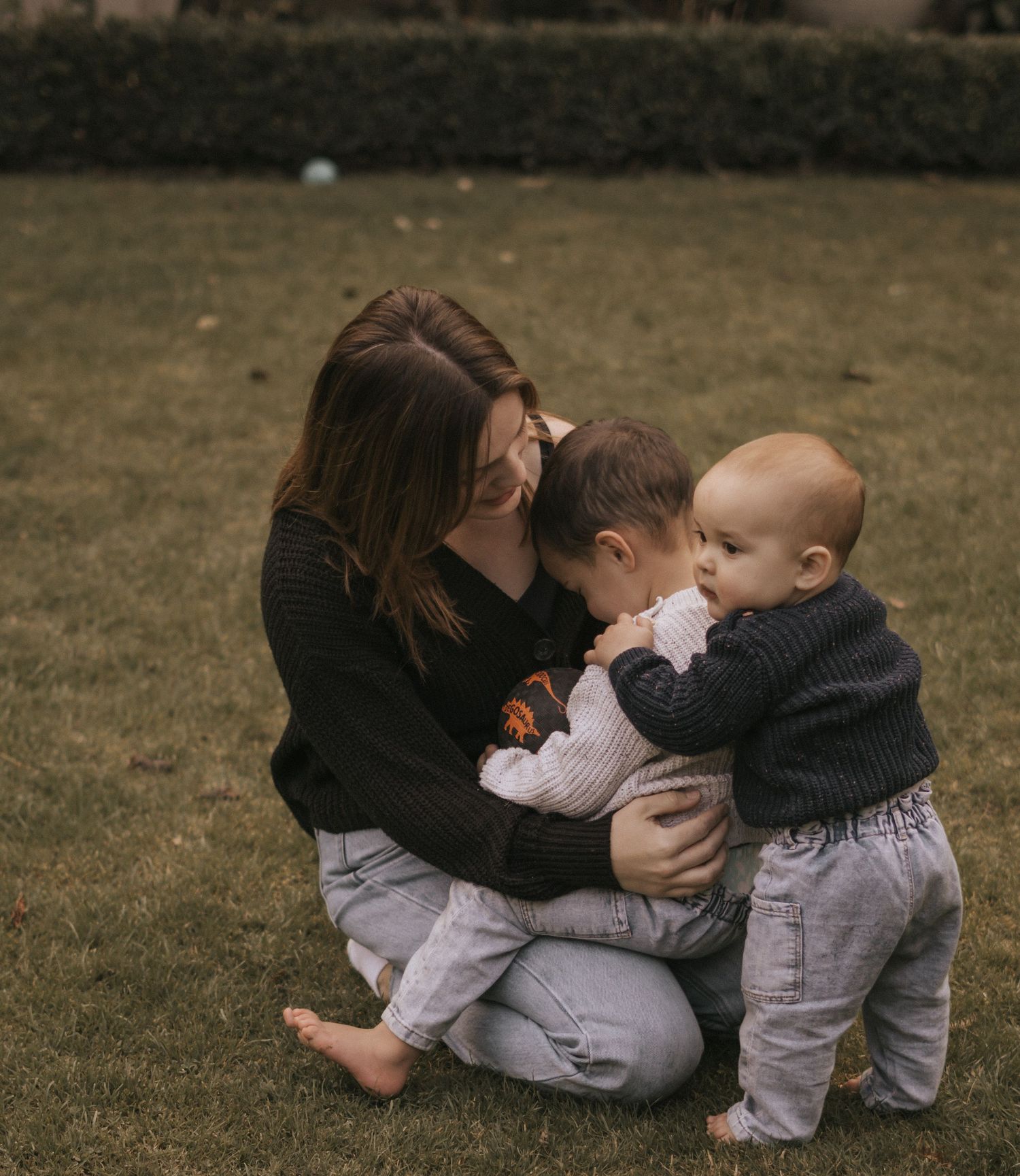 Candid outdoor photos showing tender moments between parent and child on grass.