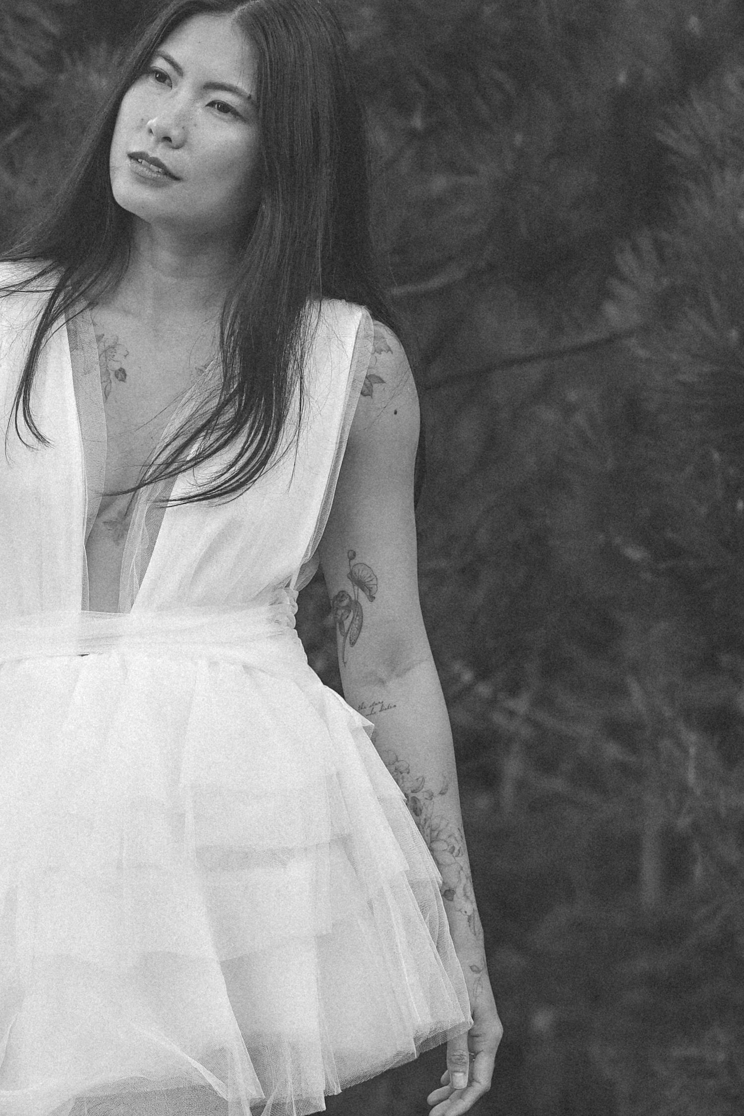 Dreamy black and white portrait featuring delicate white tulle fabric against dark background.