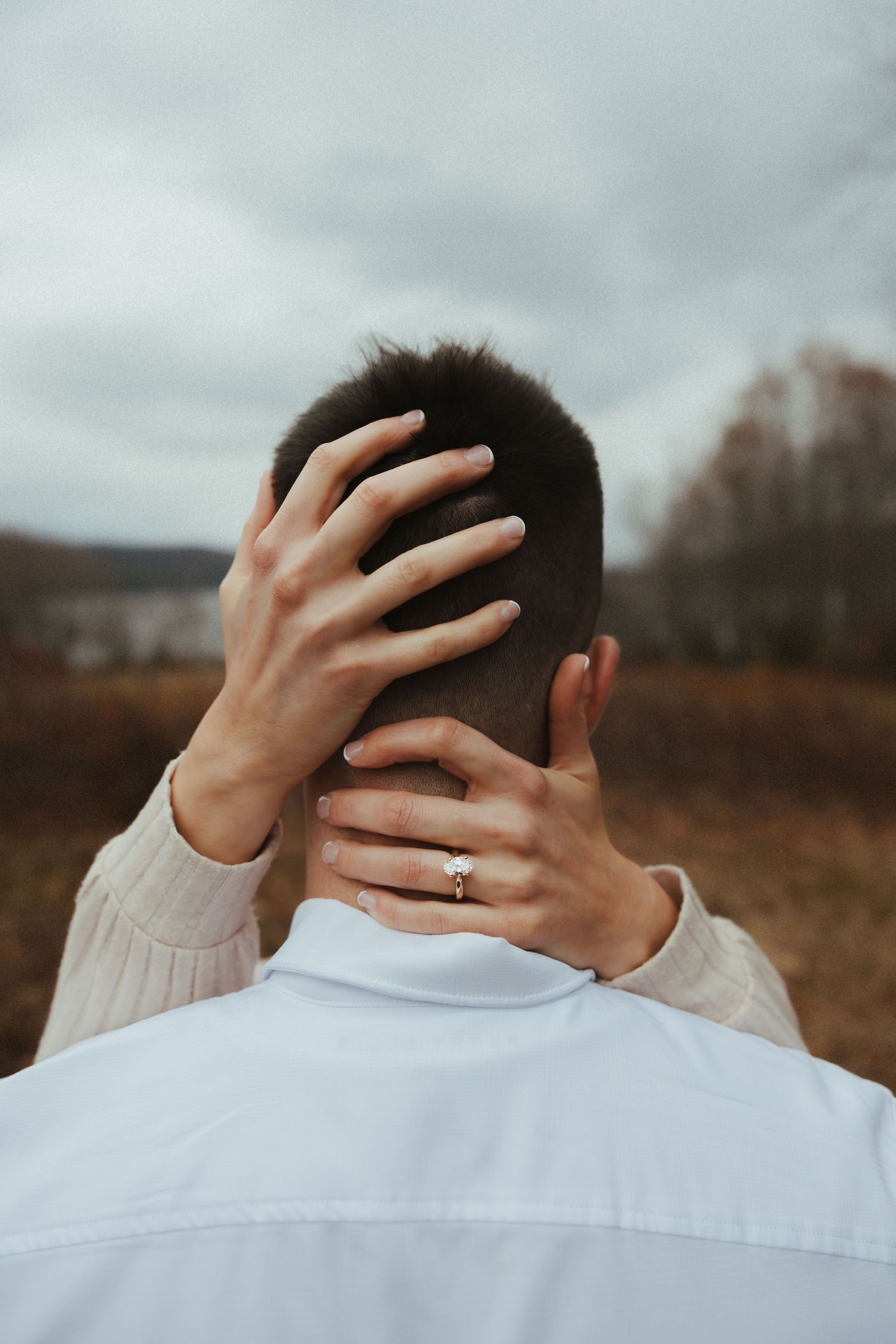 Close-up shot of someone wearing a white shirt showing off their new engagement ring.