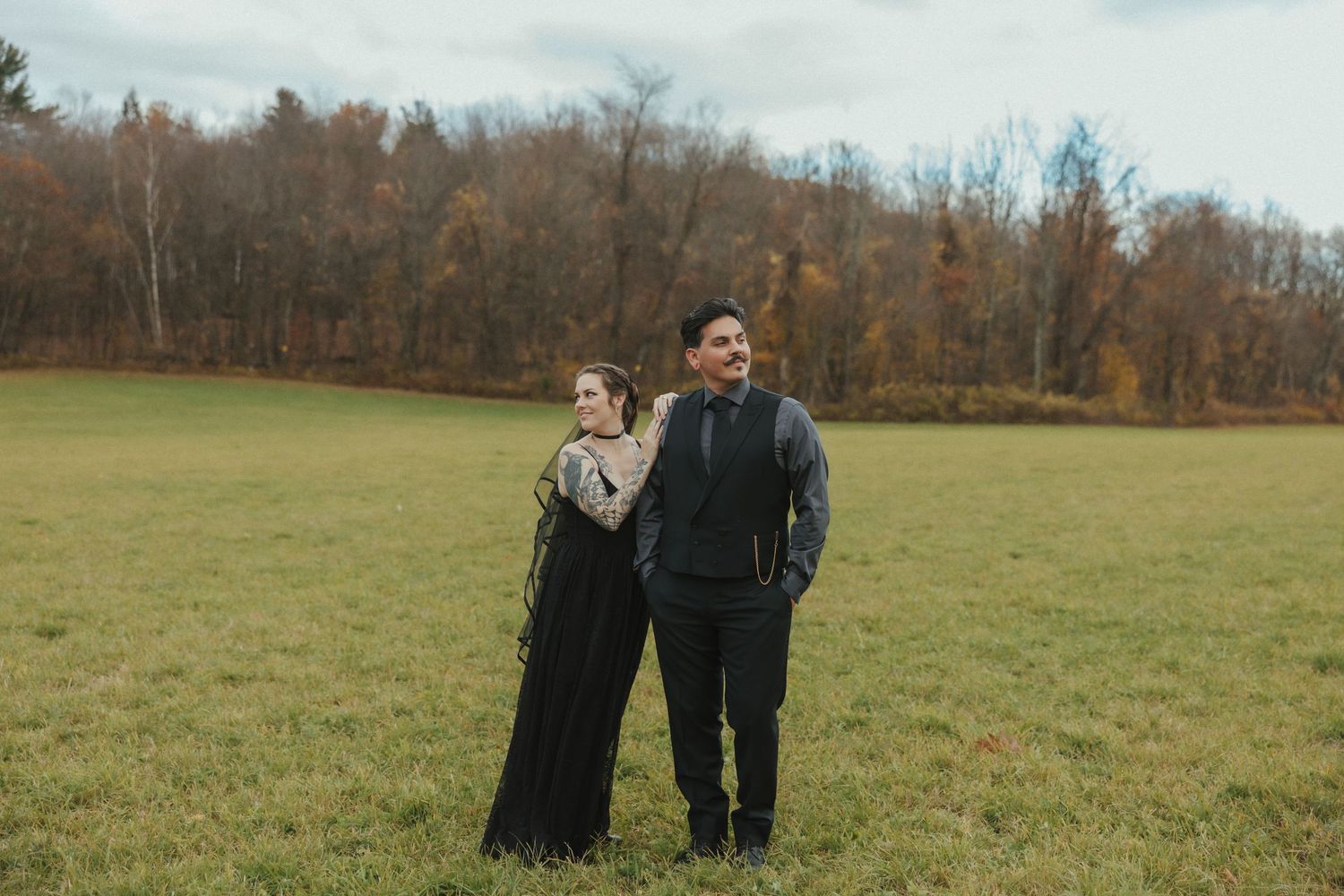 A couple shares an intimate moment in a green autumn field as they walk together during a photo session.
