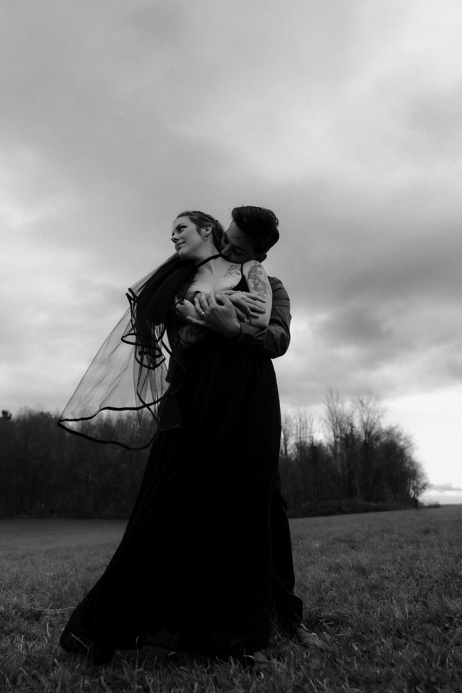 Dramatic black and white photos of figures in flowing dark dresses dancing in a misty field at dusk.