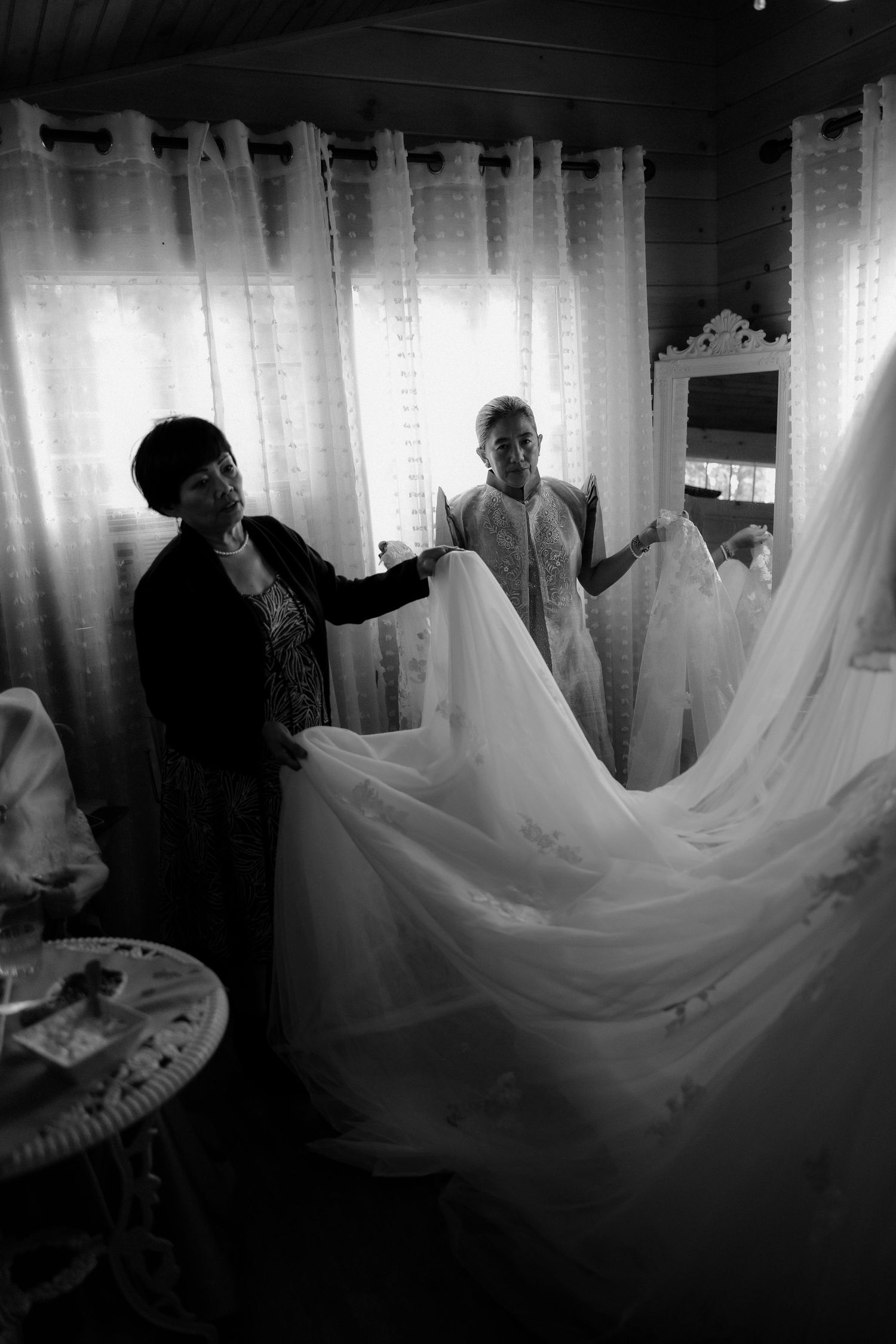 Black and white photo sequence showing wedding dress being fluffed and arranged in dramatic lighting.