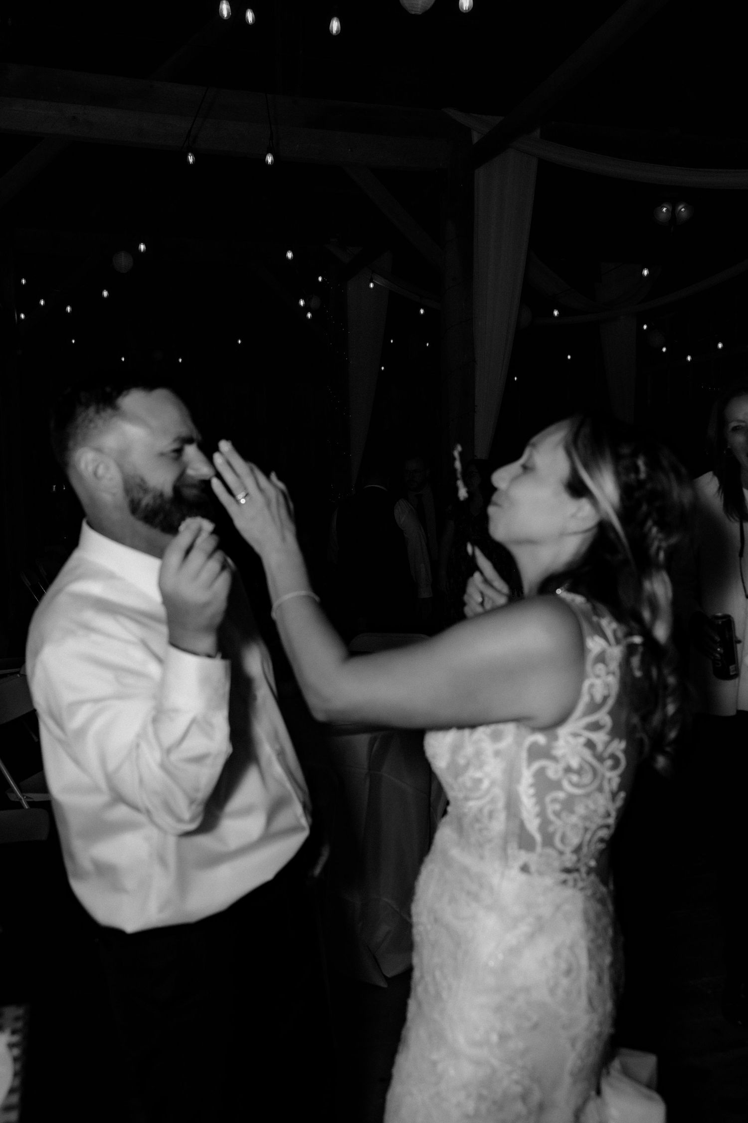 A bride and groom share a celebratory champagne toast together at their wedding reception in a darkly lit venue.