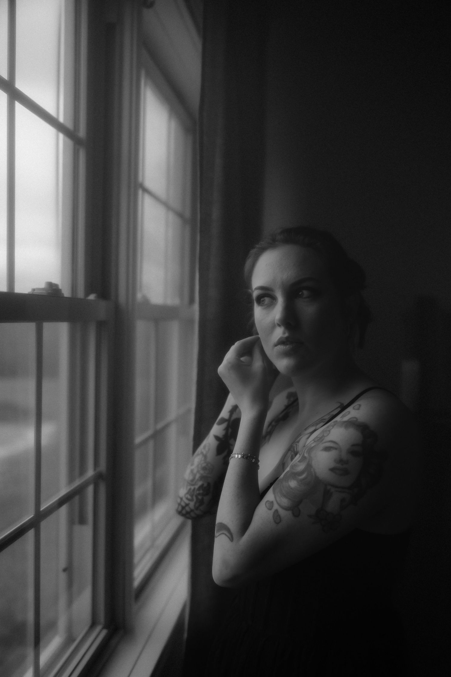 Moody black and white portrait sequence by a window with dramatic lighting and shadows.