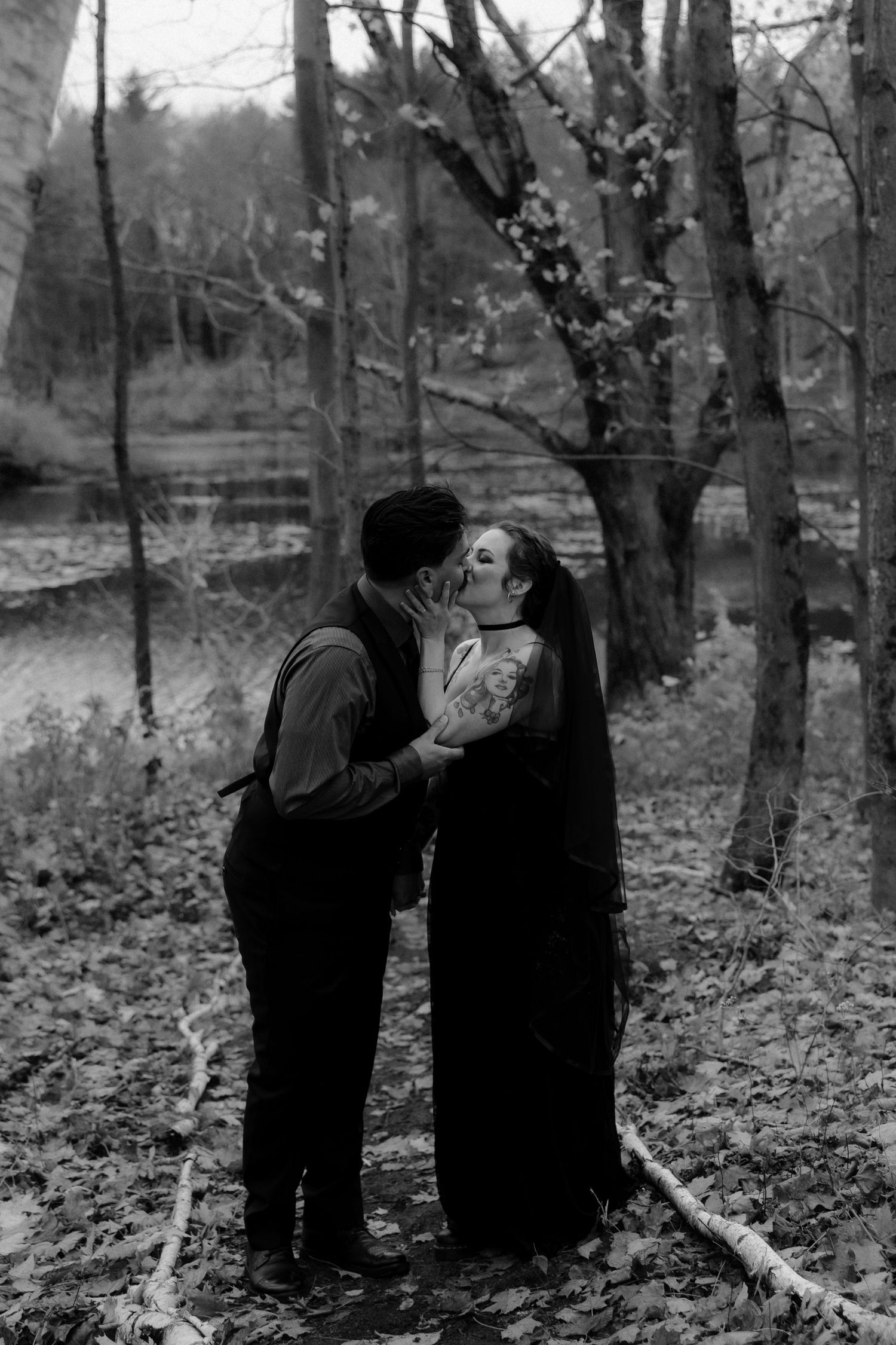 A series of black and white photos showing two figures in dark clothing embracing among bare trees in a forest setting.