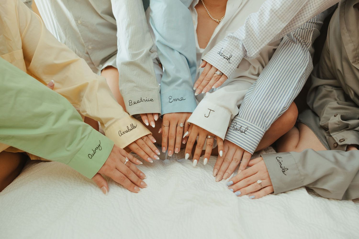 Close-up view of hands holding each other in a romantic gesture against soft neutral-toned fabric background.