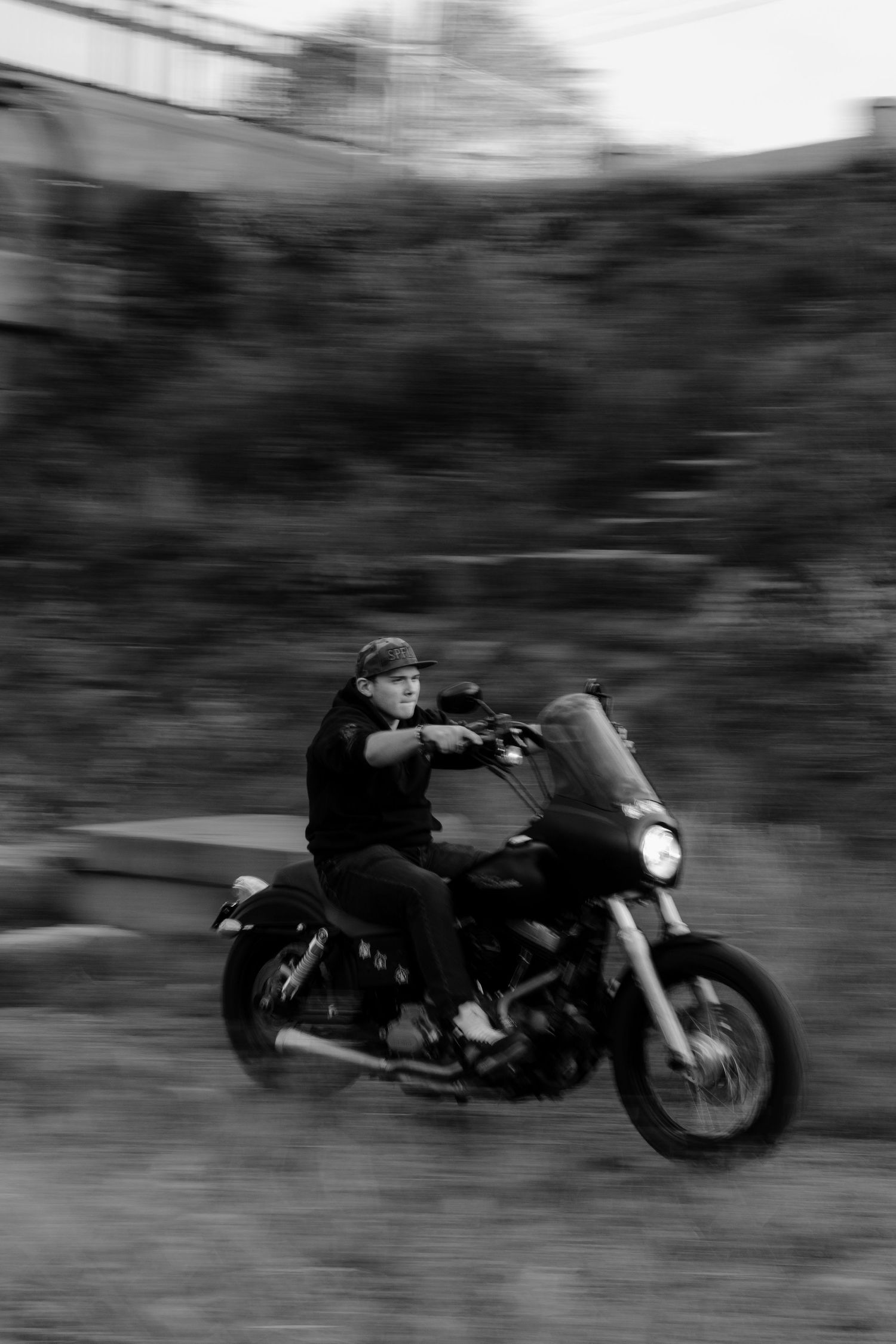Motion-blurred black and white photograph of a motorcycle speeding past, creating a dynamic sense of movement.