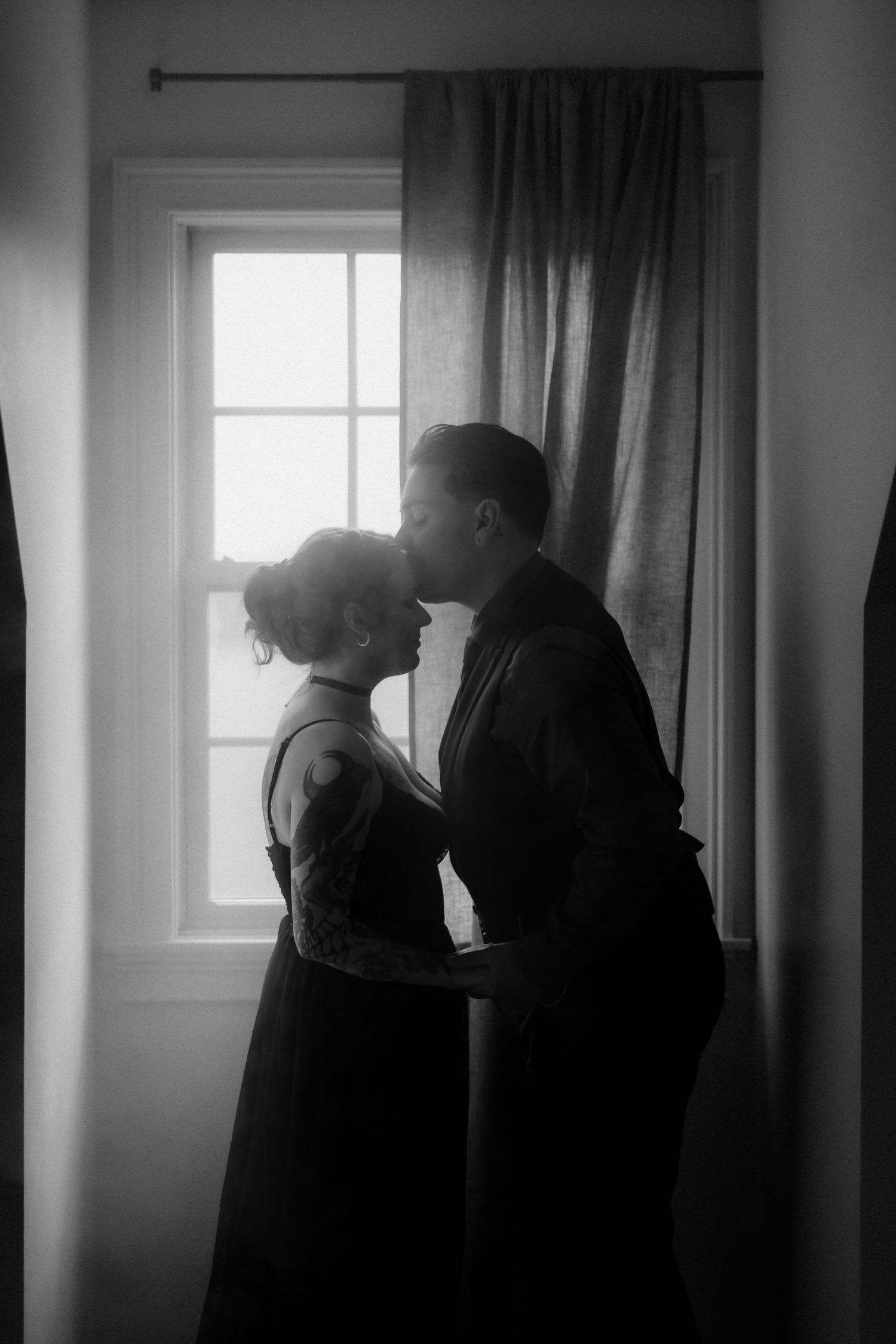 Intimate black and white sequence showing shadowy figures by a window with curtains.