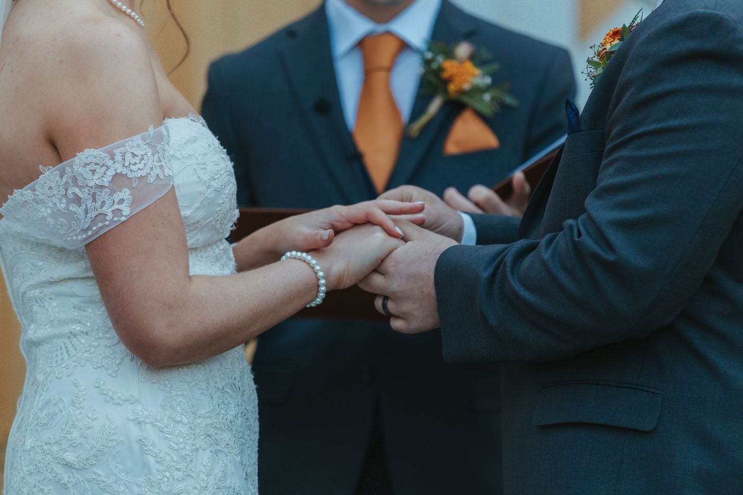 Close-up view of hands exchanging wedding rings during a traditional ceremony.