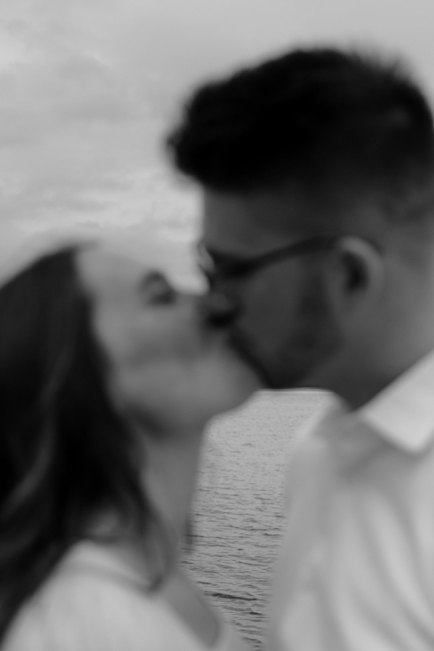 A couple embraces in a romantic black and white photo series by the water.