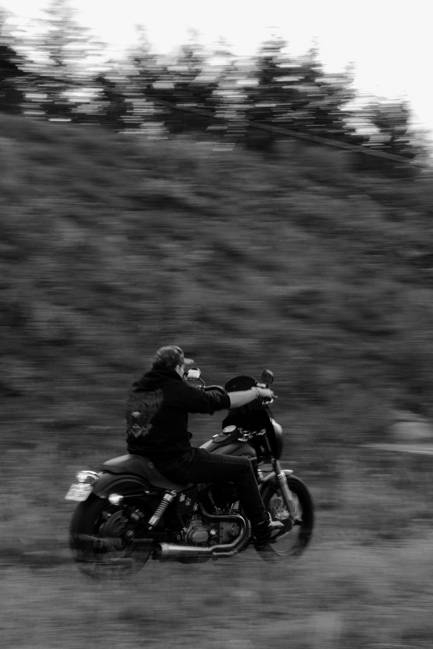 Motion-blurred sequence of a motorcycle rider leaning into a turn on a dark winding road.