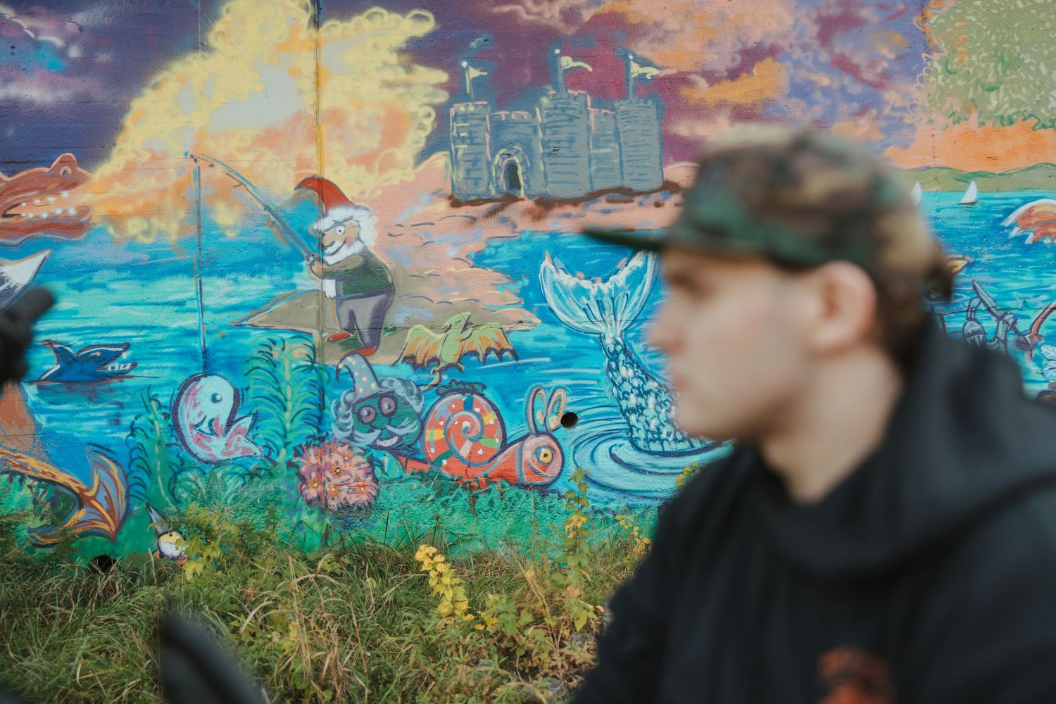 Colorful ocean-themed street art mural featuring underwater scenes with sea creatures and vibrant sunset colors.