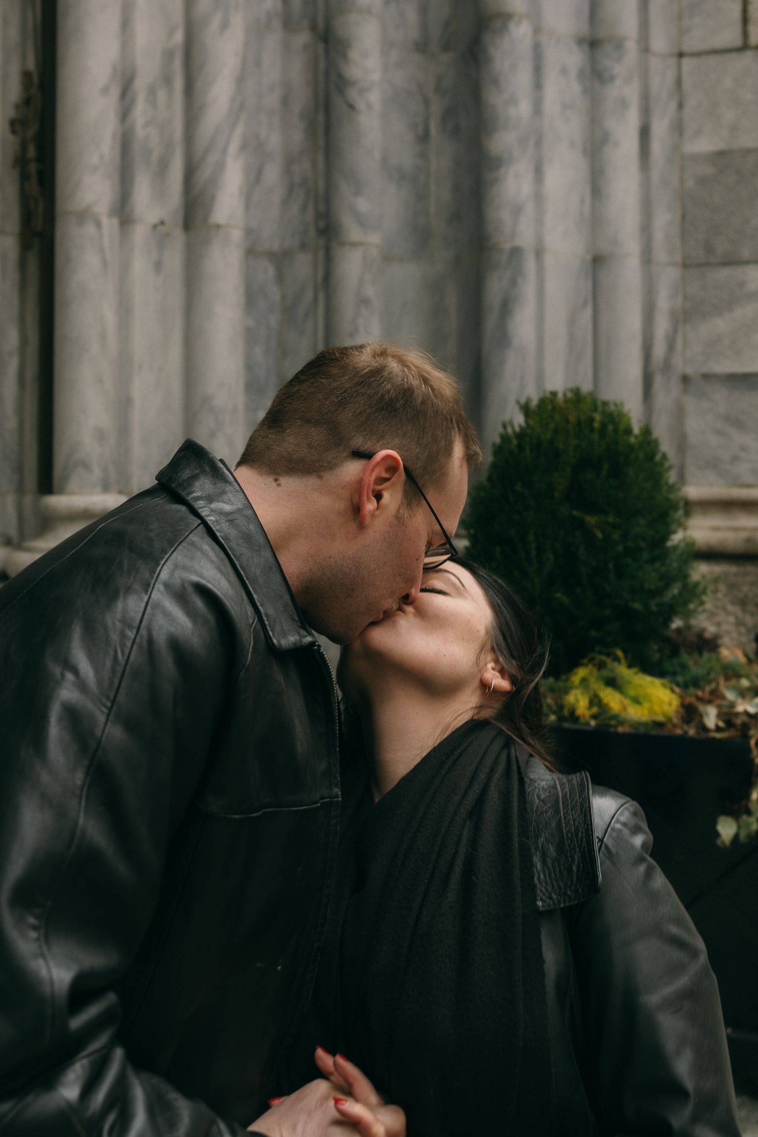 Intimate couple sharing romantic moments against stone wall backdrop.