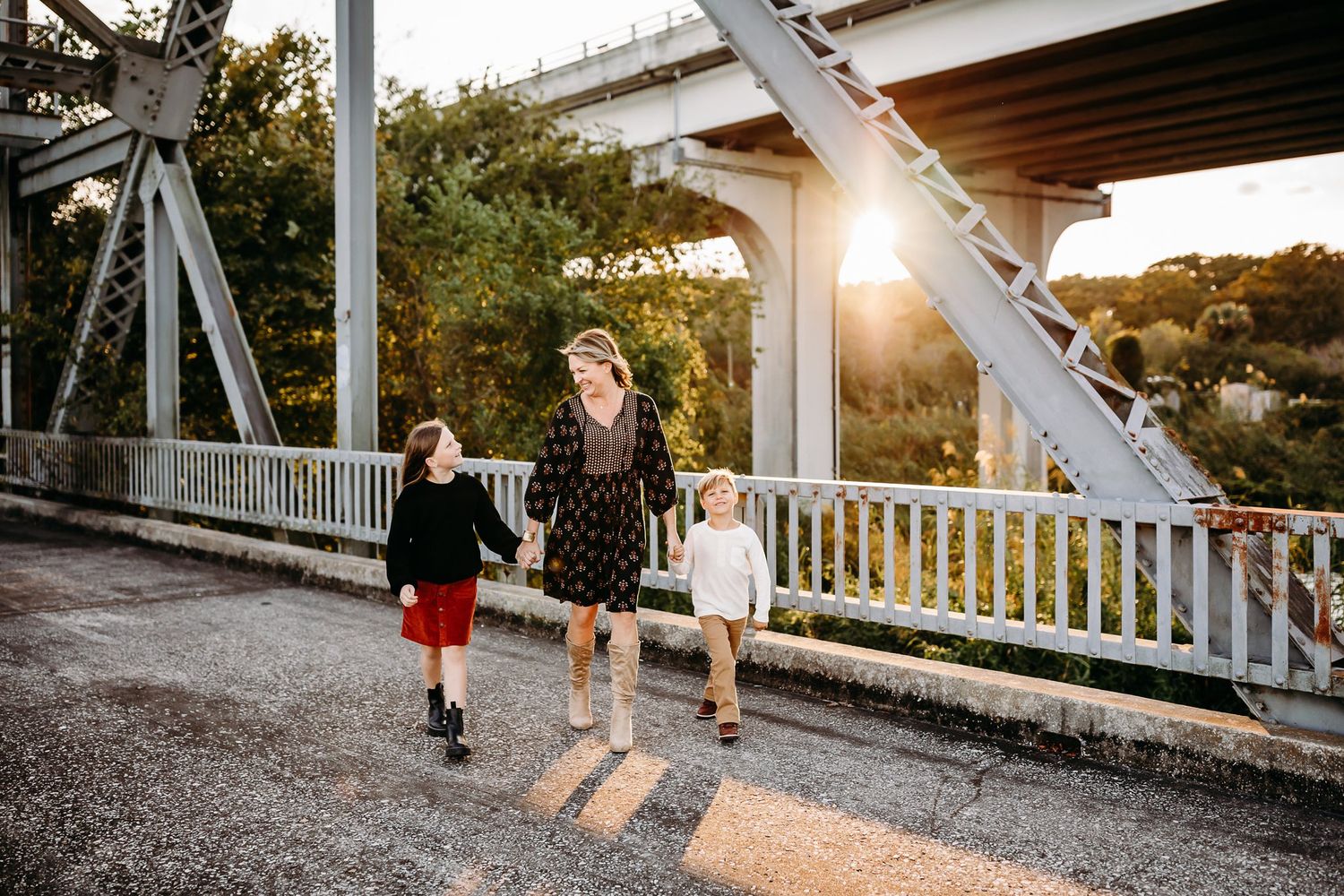 Couple walking together at sunset on a rustic bridge with beautiful golden light peeking through the trees.