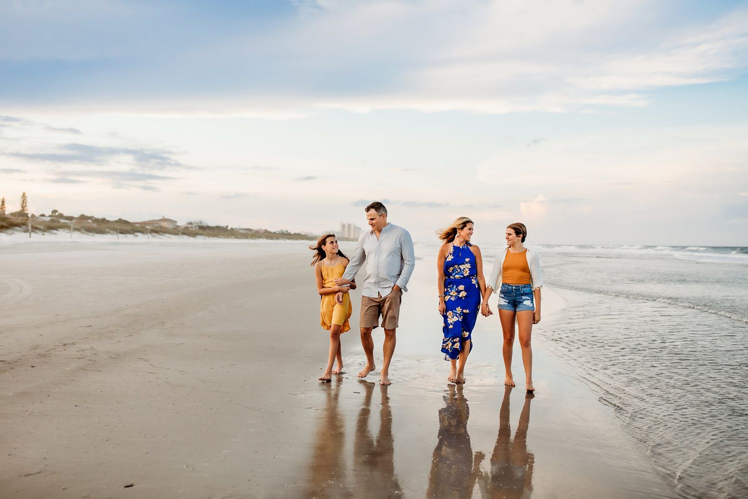 Group of friends walking along the shoreline at sunset on a peaceful beach.