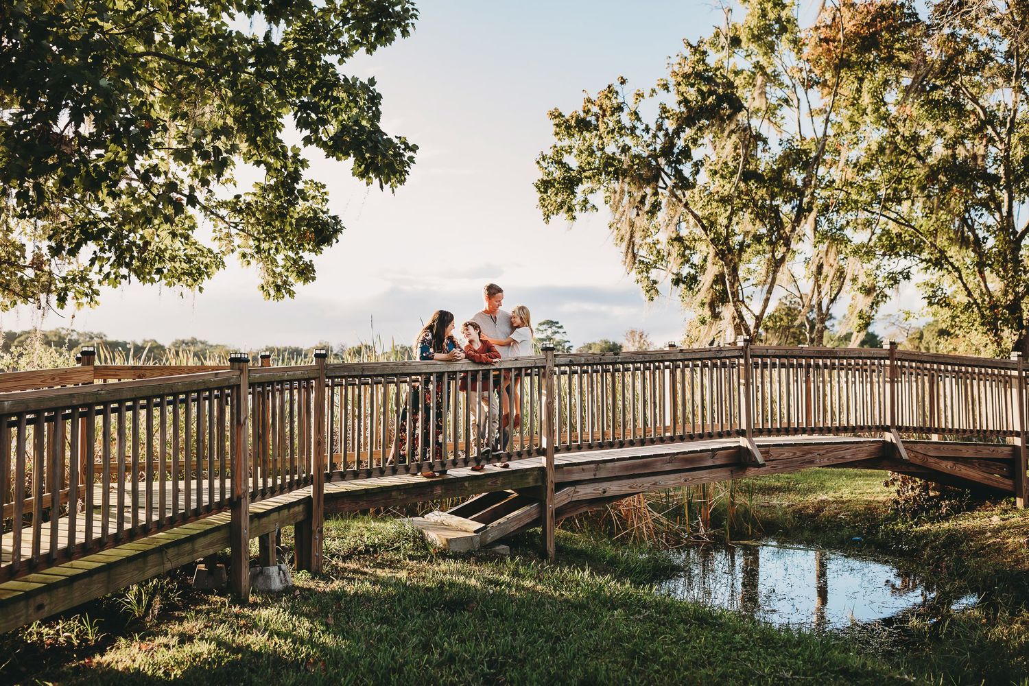 Scenic panoramic view of a bridge walkway in a park during autumn with golden foliage and sunny skies.