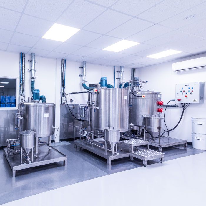 Technical photography of steel paint mixing vats in a sterile clean room environment.