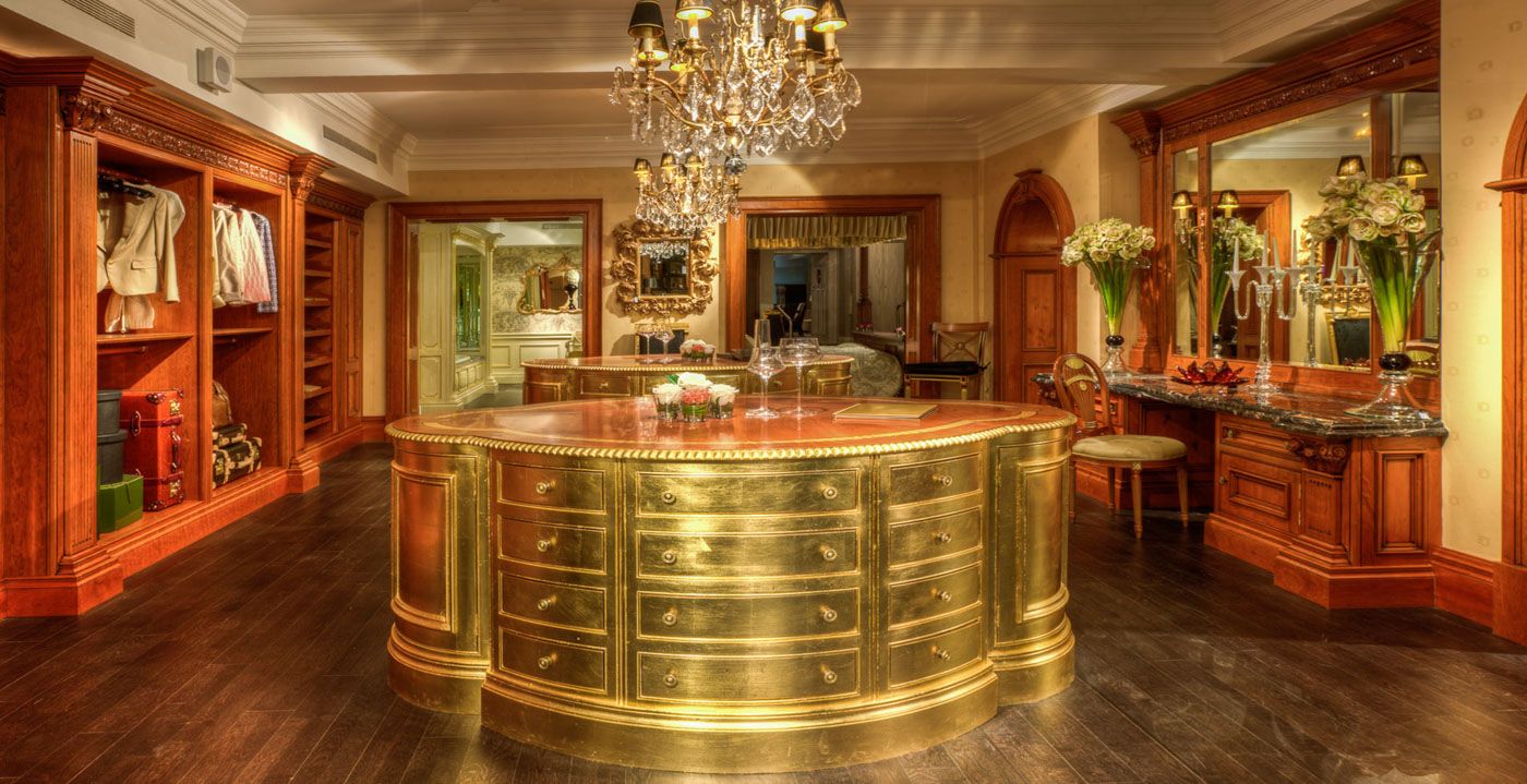 Luxurious retail store interior with curved brass counter, crystal chandelier, and rich wooden display cabinets.