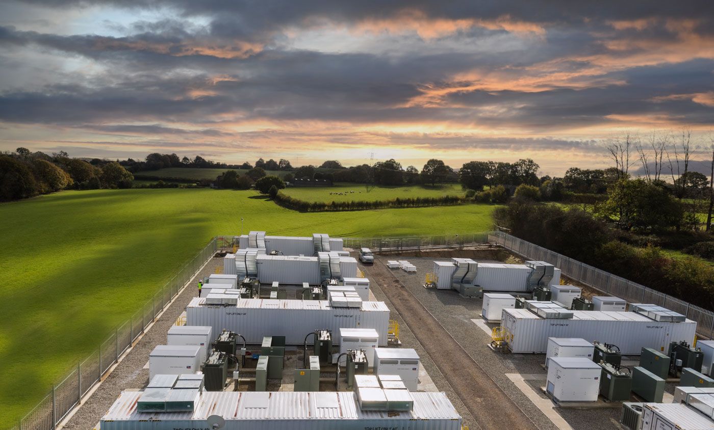 Sunset view over green sports field with industrial HVAC units mounted on rooftop in foreground.