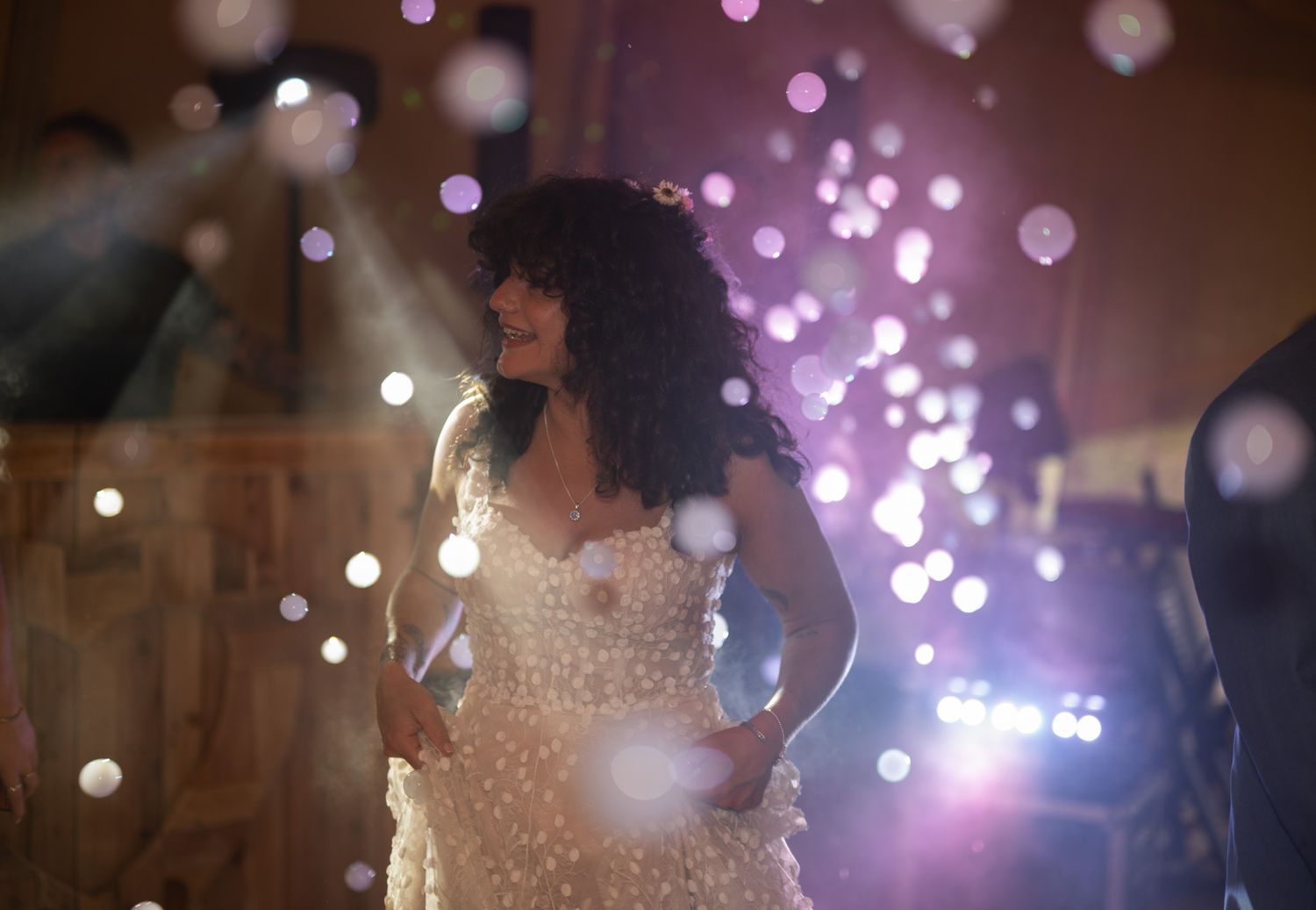 Woman in sparkly white gown dancing under bokeh lights at an elegant evening event.