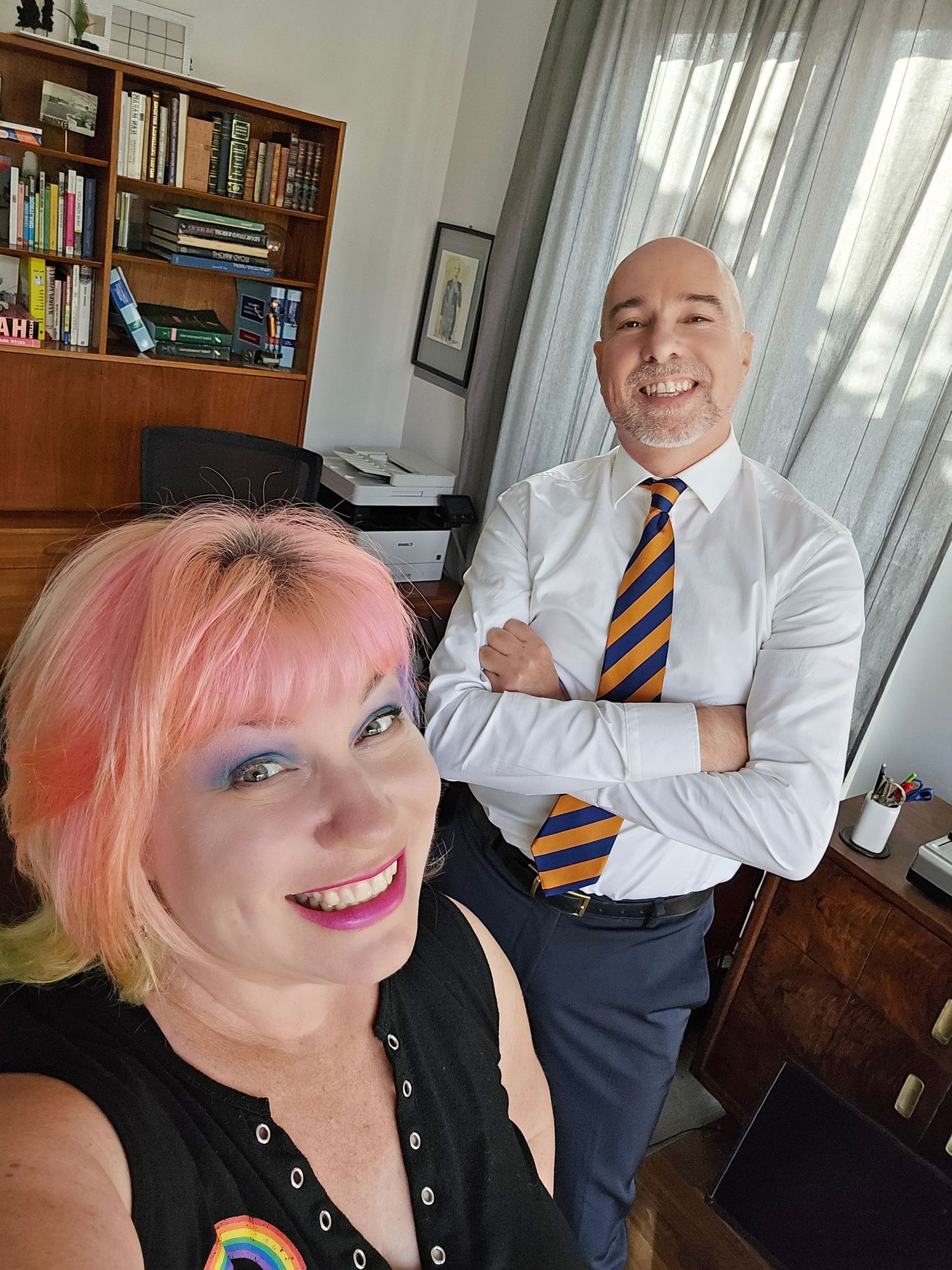 A series of selfie photos showing someone with pink hair and a person in a white shirt with a striped tie in an office setting.