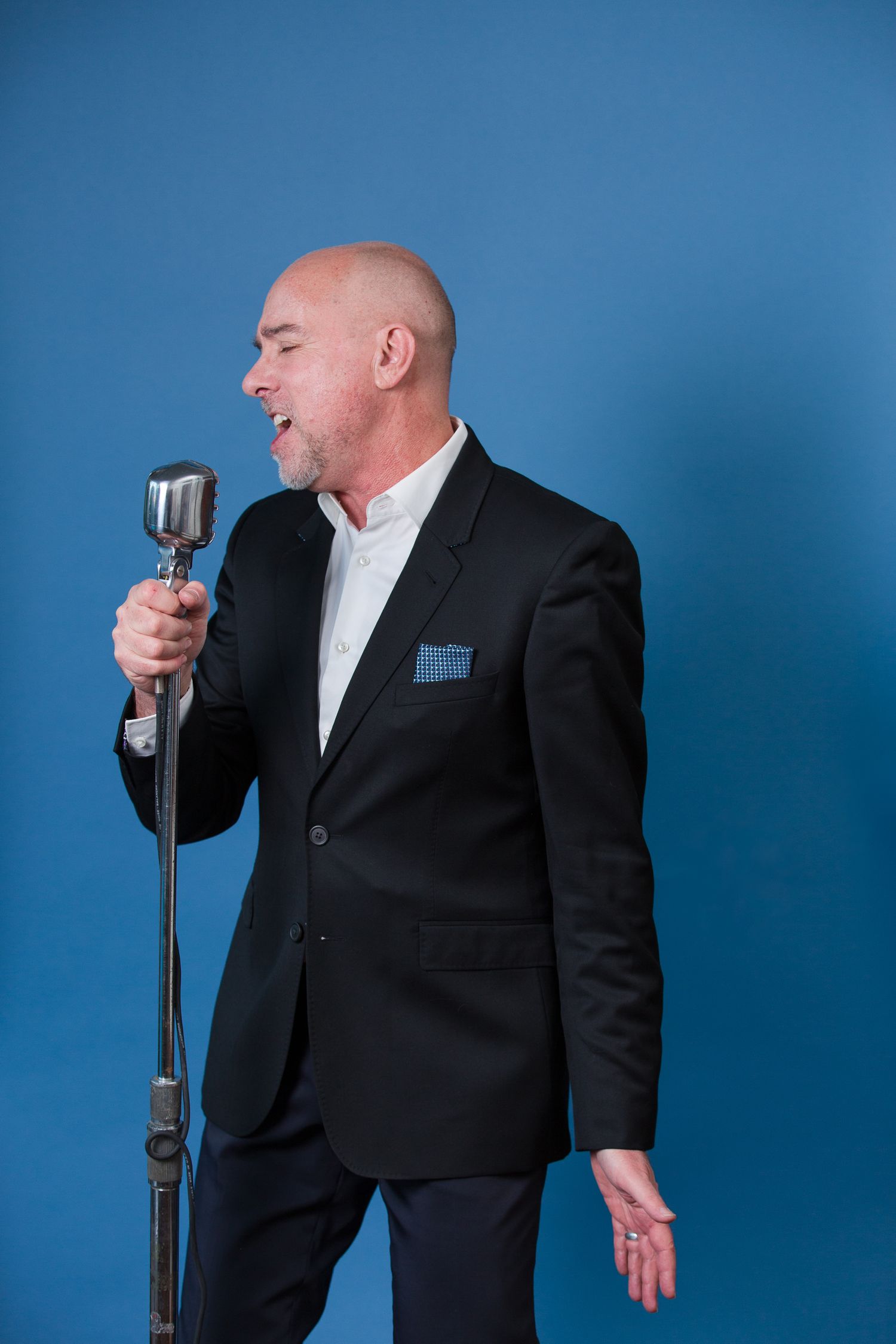 Studio photoshoot sequence showing expressive performance with vintage microphone against blue background.