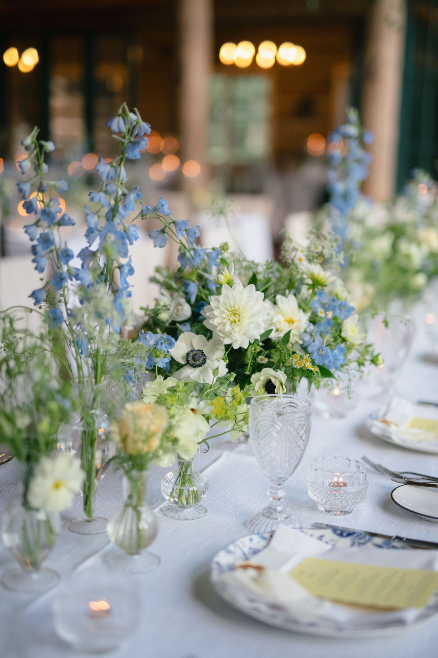 Elegant wedding table settings with blue and white floral centerpieces and crystal glassware.