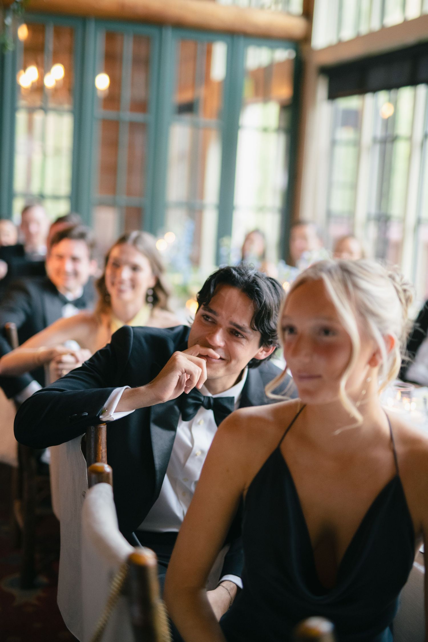 Wedding guests enjoying a candid moment at an indoor reception venue.