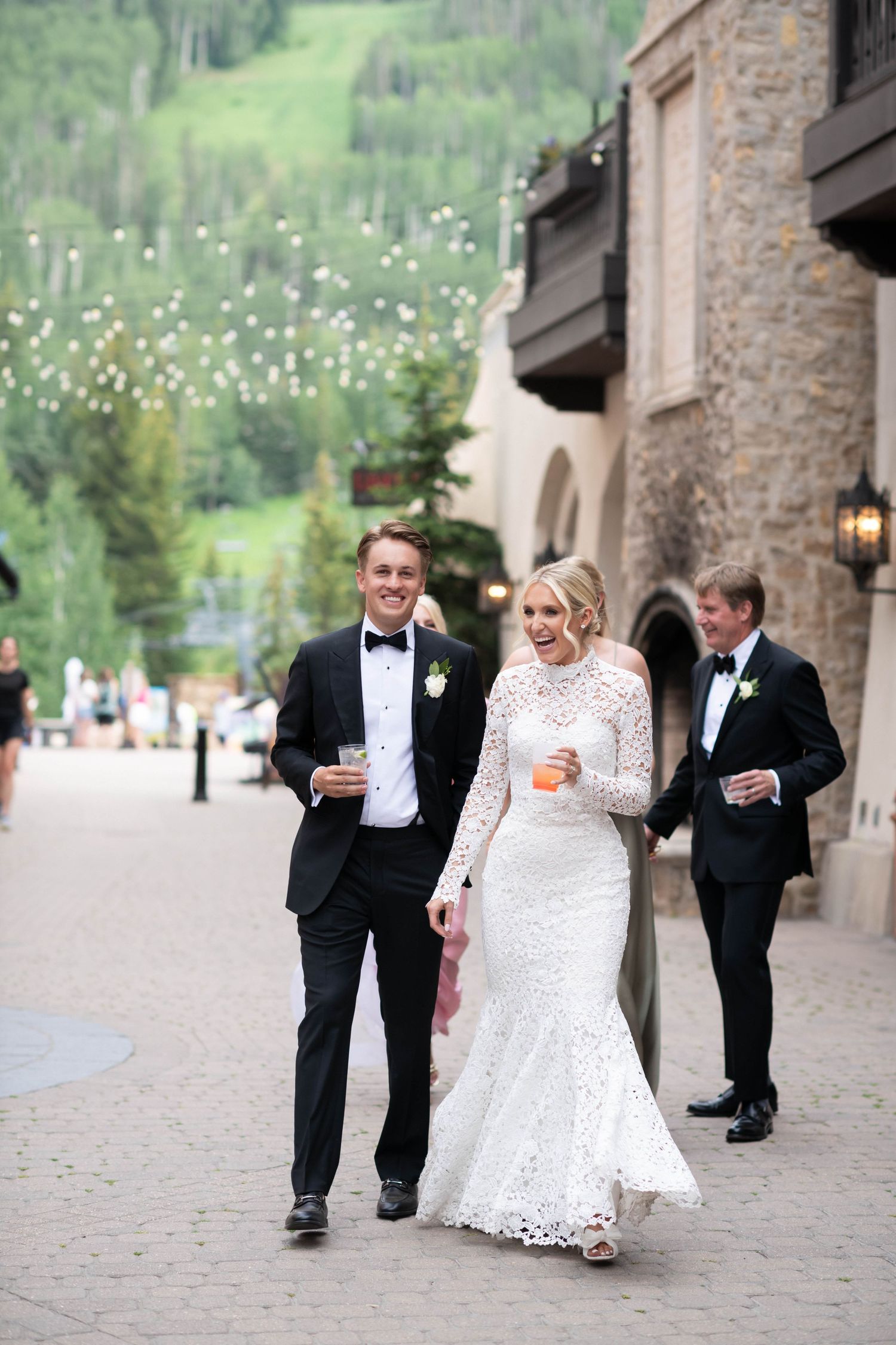 Wedding party walking along a stone building pathway in formal attire.
