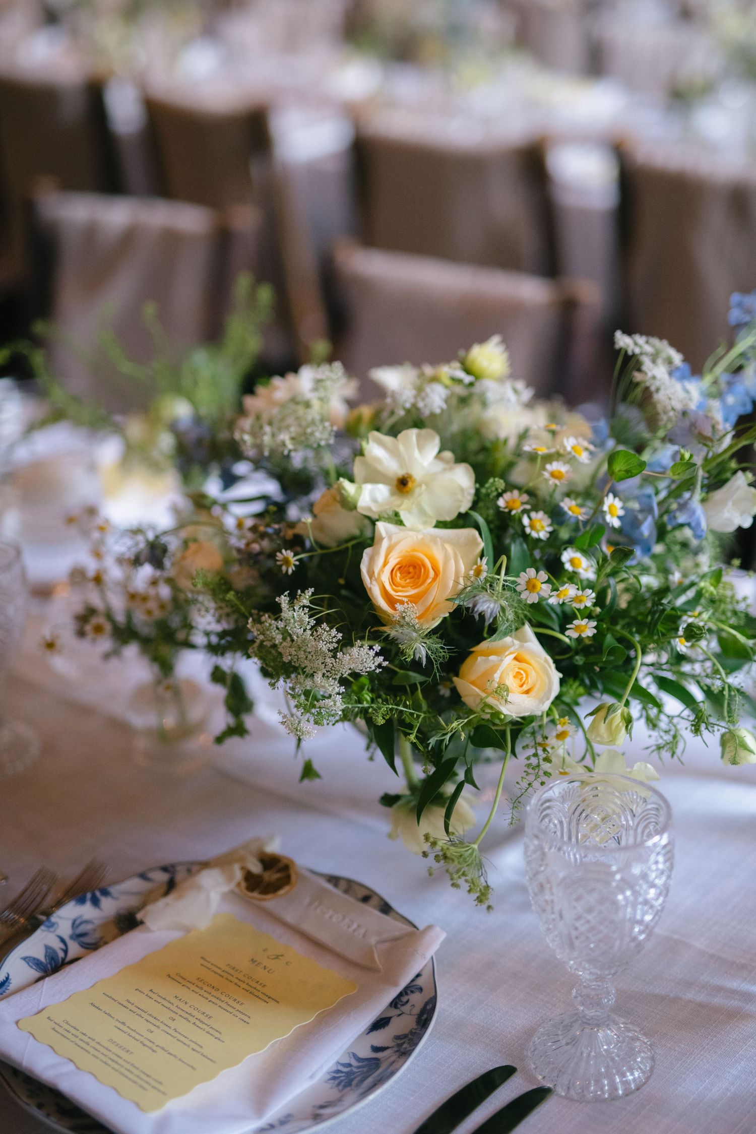 Wedding table setting with yellow roses and printed menu cards.